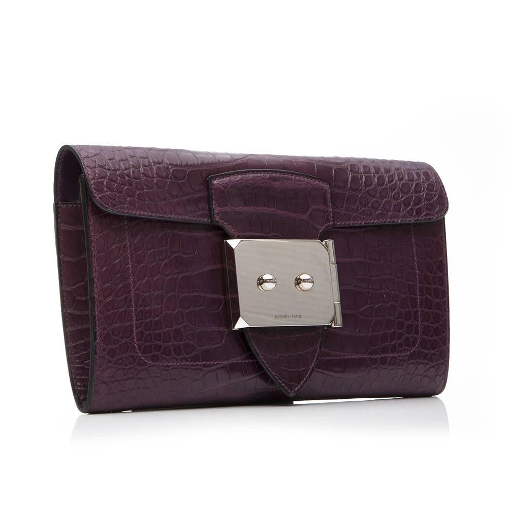 Hermes Goodlock clutch in Amethyst alligator leather featuring palladium hardware and a detachable wrist strap. The front lock is stamped with 'Hermes Paris' and the interior of the lock will retains its protective plastic. The interior of the bag