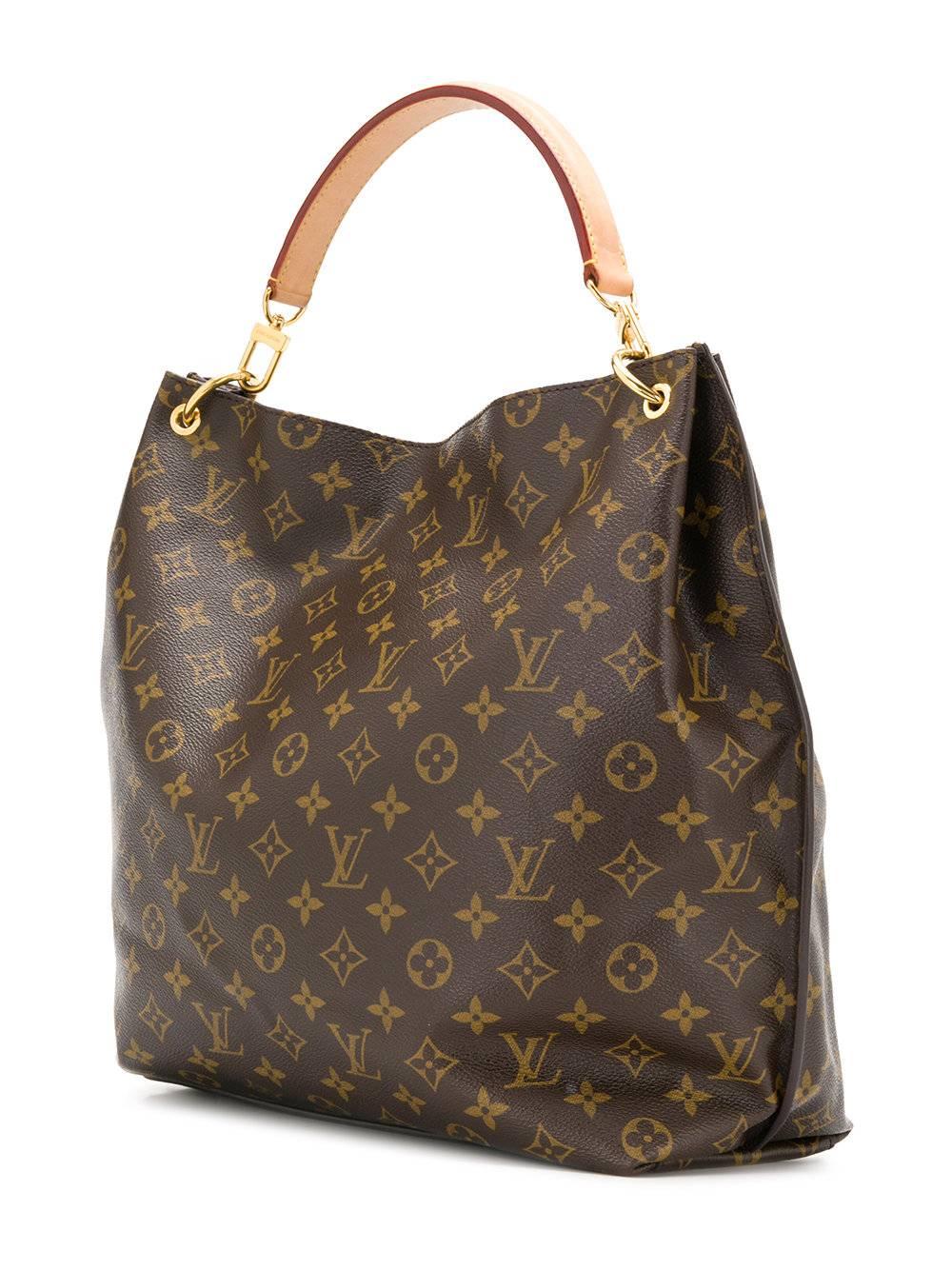 Crafted in the iconic brown monogram canvas print, this luxurious leather tote bag by Louis Vuitton features a wide open-top design, a front flap pocket accented by the brands signature S-Lock closure in gold-tone hardware and a removable vachetta