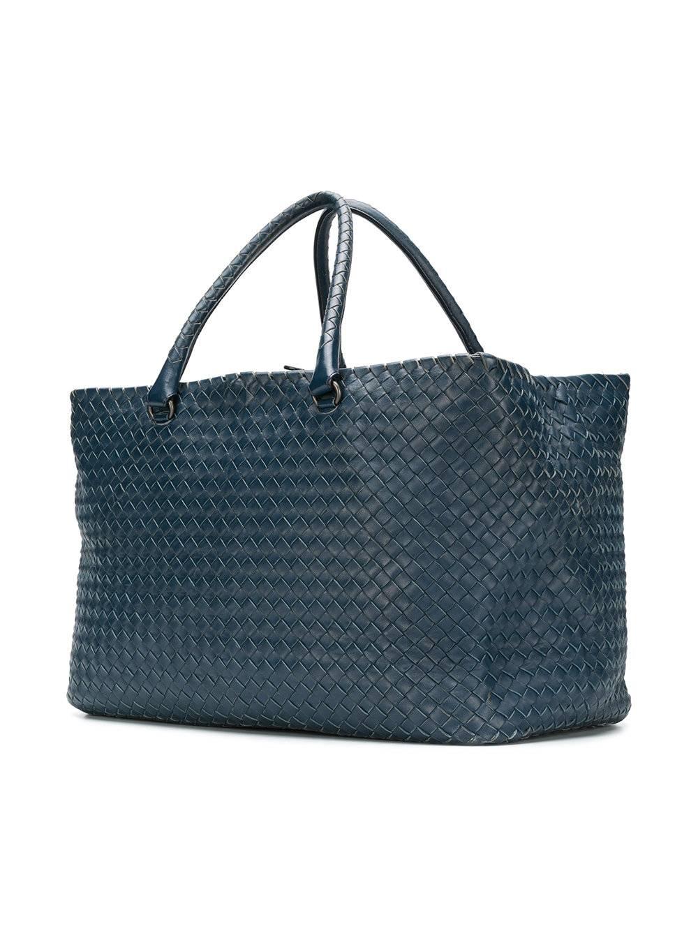 This woven duffle bag by Bottega Veneta Vintage, designed to resist wear and tear is stylish yet functional. Crafted in a navy lambskin, the piece features Bottega’s signature woven leather exterior in a convenient silhouette and comes with pure