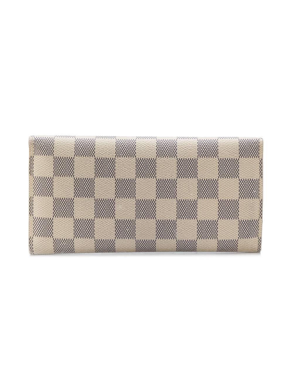 Fashioned in Damier Azur canvas, this stylish yet spacious wallet by Louis Vuitton features an envelope design, a foldover top with snap closure, a calf-leather lining, an interior zipped compartment, multiple interior card slots and an internal
