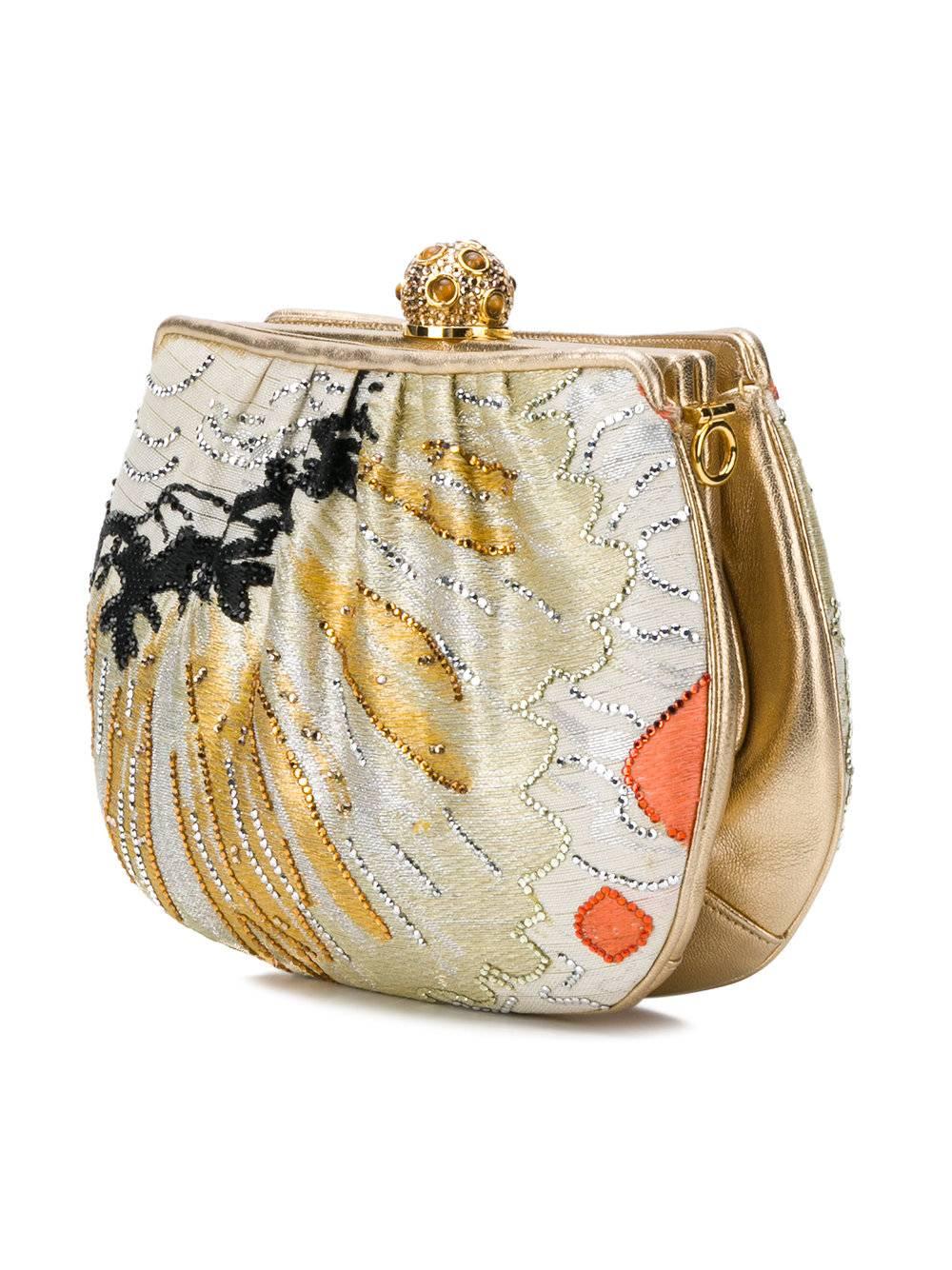 The iconic Judith Leiber imparts her extraordinary, glittering sensibility to this design. Made so desirable in its luxuriant textures of satin, gold leather and Austrian crystal strass, the box-shaped clutch is patterned in painterly strokes, and