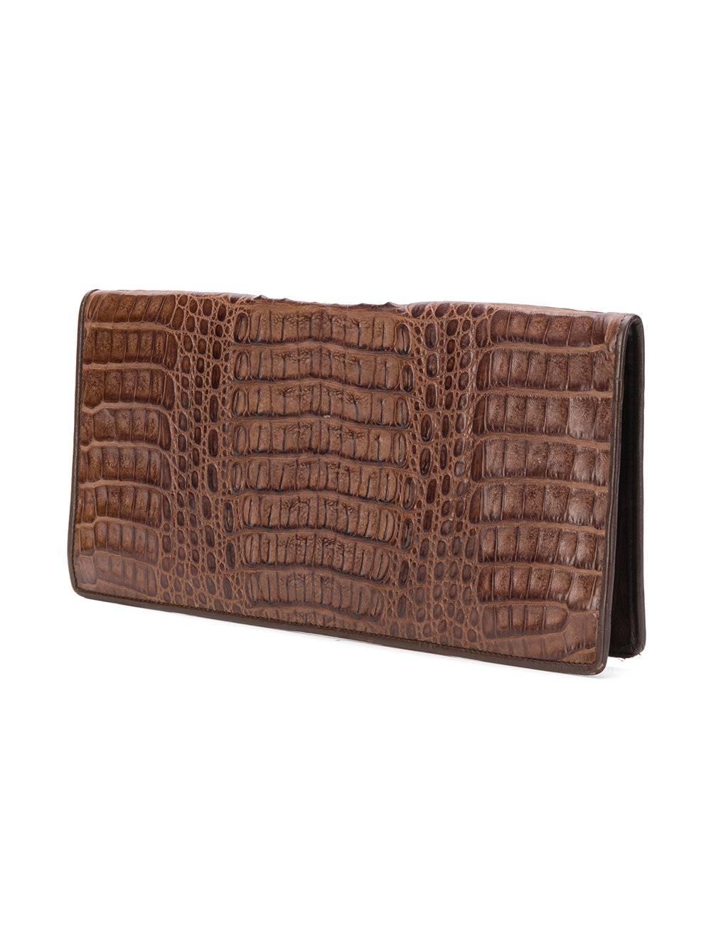 A timeless vintage clutch crafted from an exquisite and unusually patterned brown crocodile leather, offset with a co-ordinated leather lining. It opens with a magnetic fastening, and features an interior pocket lined with brown satin, and a small