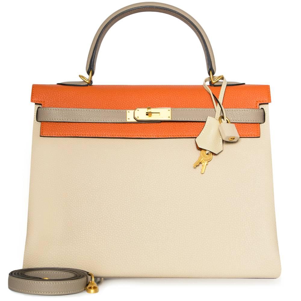 Crafted in Togo leather, this rare, limited edition of the Hermès Tri-Colour Kelly bag features three assorted colours across its silhouette; a neutral gris touterelle body and vibrant orange poppy top flap is offset by etoupe leather handles, belt