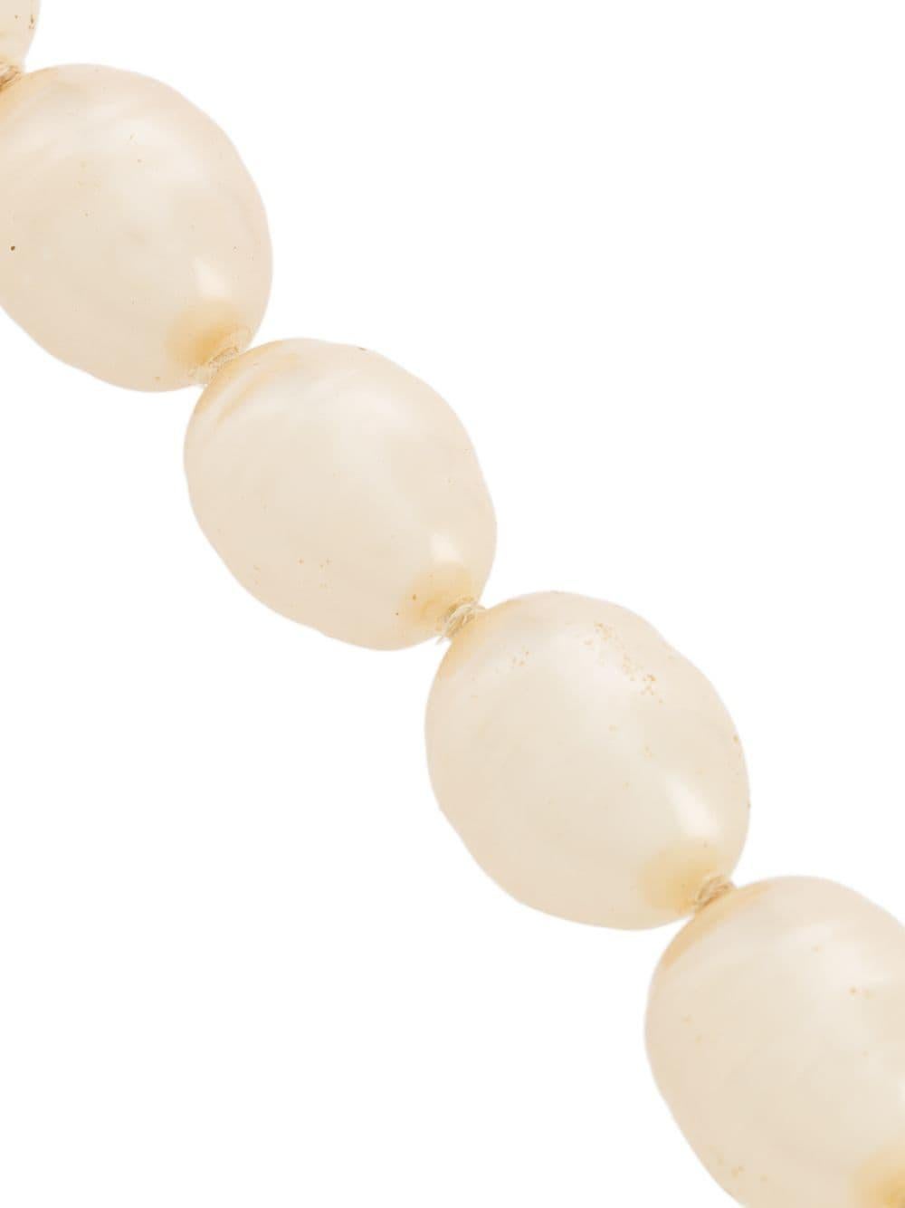 Crafted back in 1993, this timeless pearl necklace is classic and sophisticated. In a distinguished buff tone, these oval-shaped faux pearls have a medium size, which perfectly matches the short length of this lovely jewellery. The toggle fastening