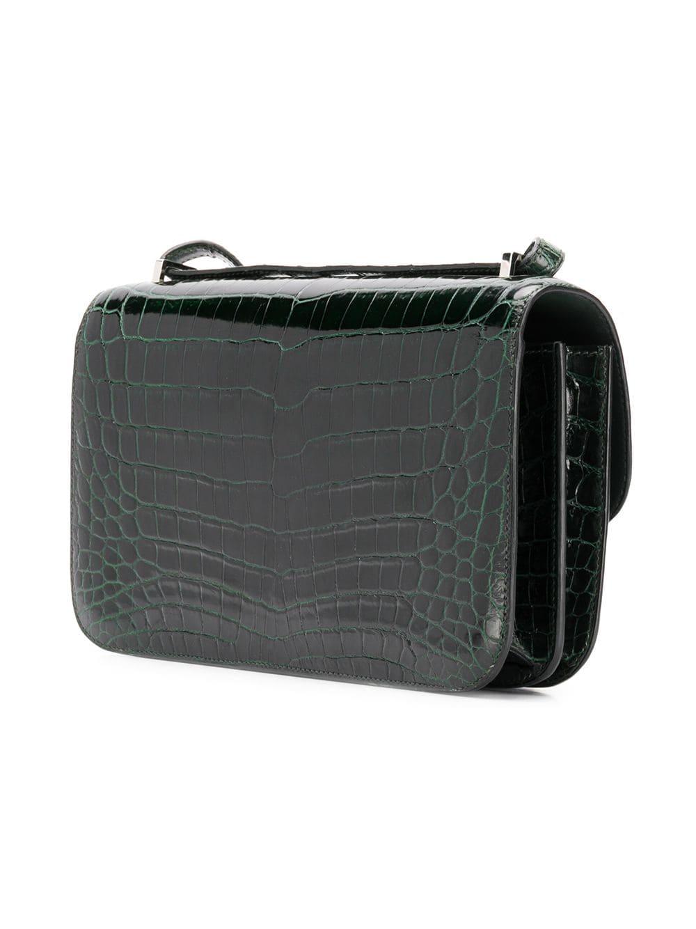 This 25cm Constance Elan shoulder bag from Hermès was meticulously crafted in France from a highly precious Niloticus crocodile in a deep shade of forest green. Offset with silver-tone palladium-plated hardware, its slender body is adorned with the