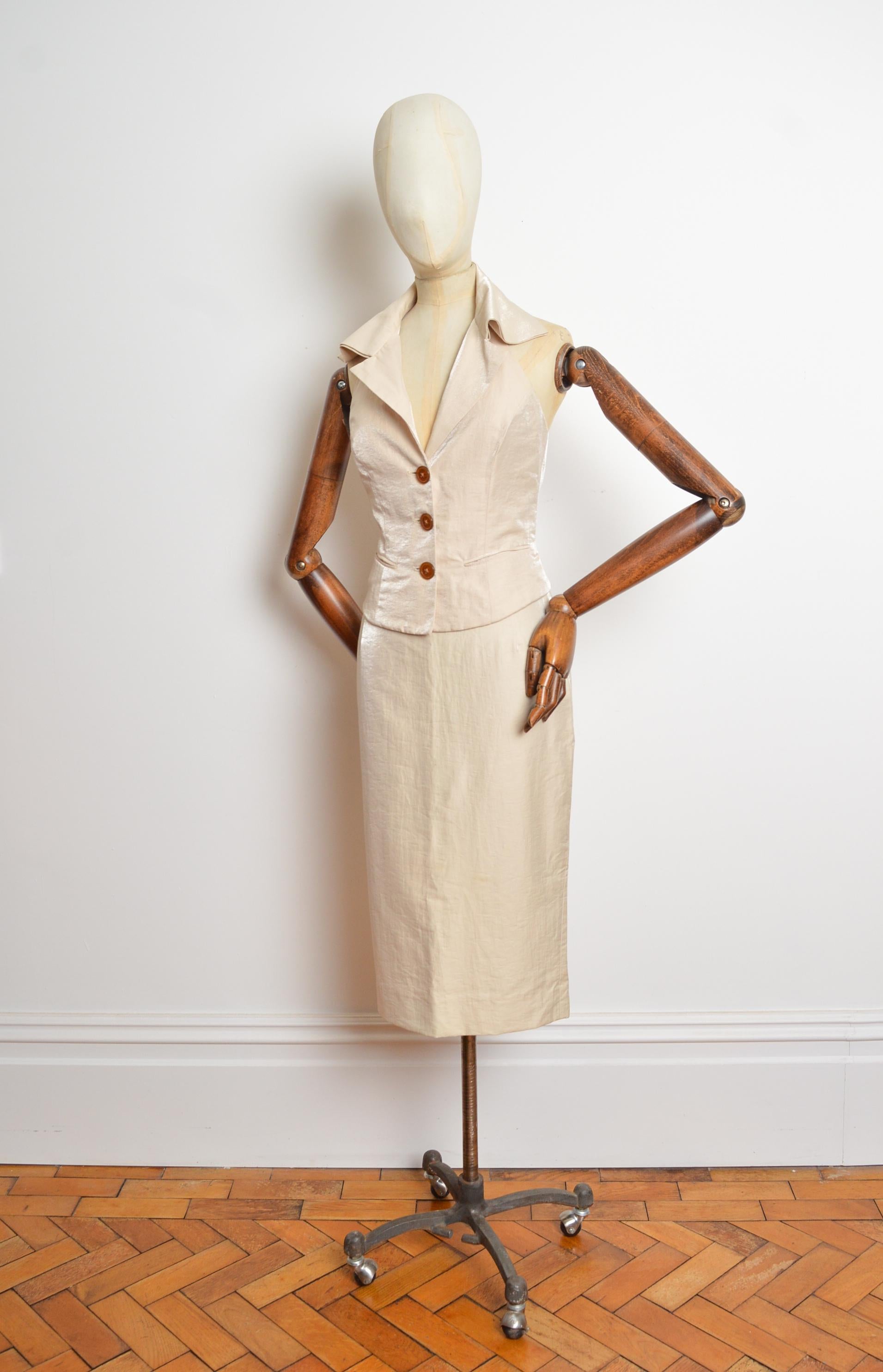 Primavera / Estate 2004 Vivienne Westwood Red label Gilet senza schienale e gonna a matita a vita alta color champagne. 
Questa stoffa di colore bianco sporco/avorio ha una leggera lucentezza. 
Taglia; consigliamo UK 6
Le misure sono indicate in
