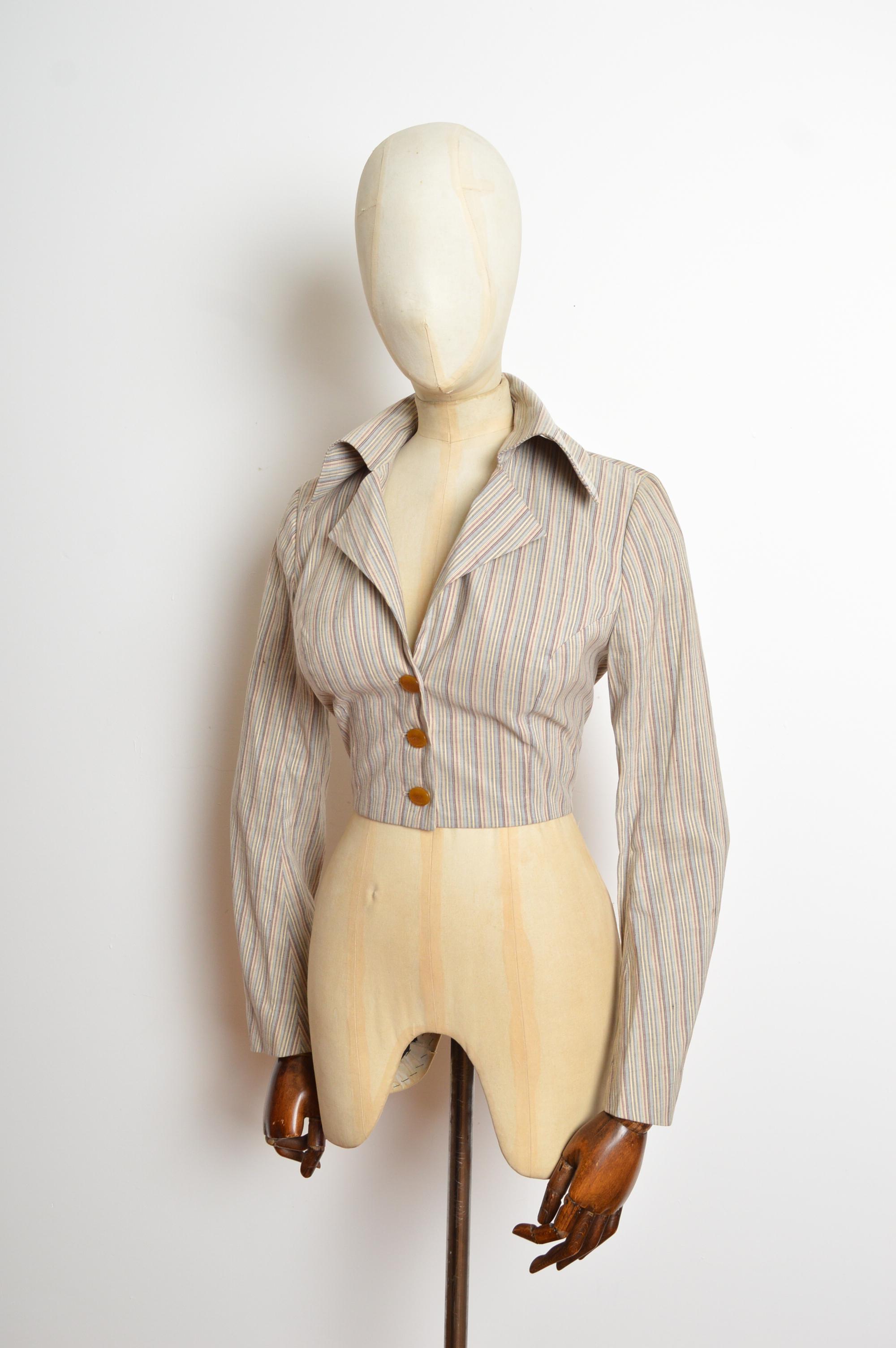 Un bellissimo Vivienne Westwood della metà degli anni '90.  Giacca in lino a righe nei toni del blu, bianco e malva, con una semplice fodera in cotone. La giacca presenta una silhouette aderente con gli iconici grandi bottoni Orb al centro. 
Taglia
