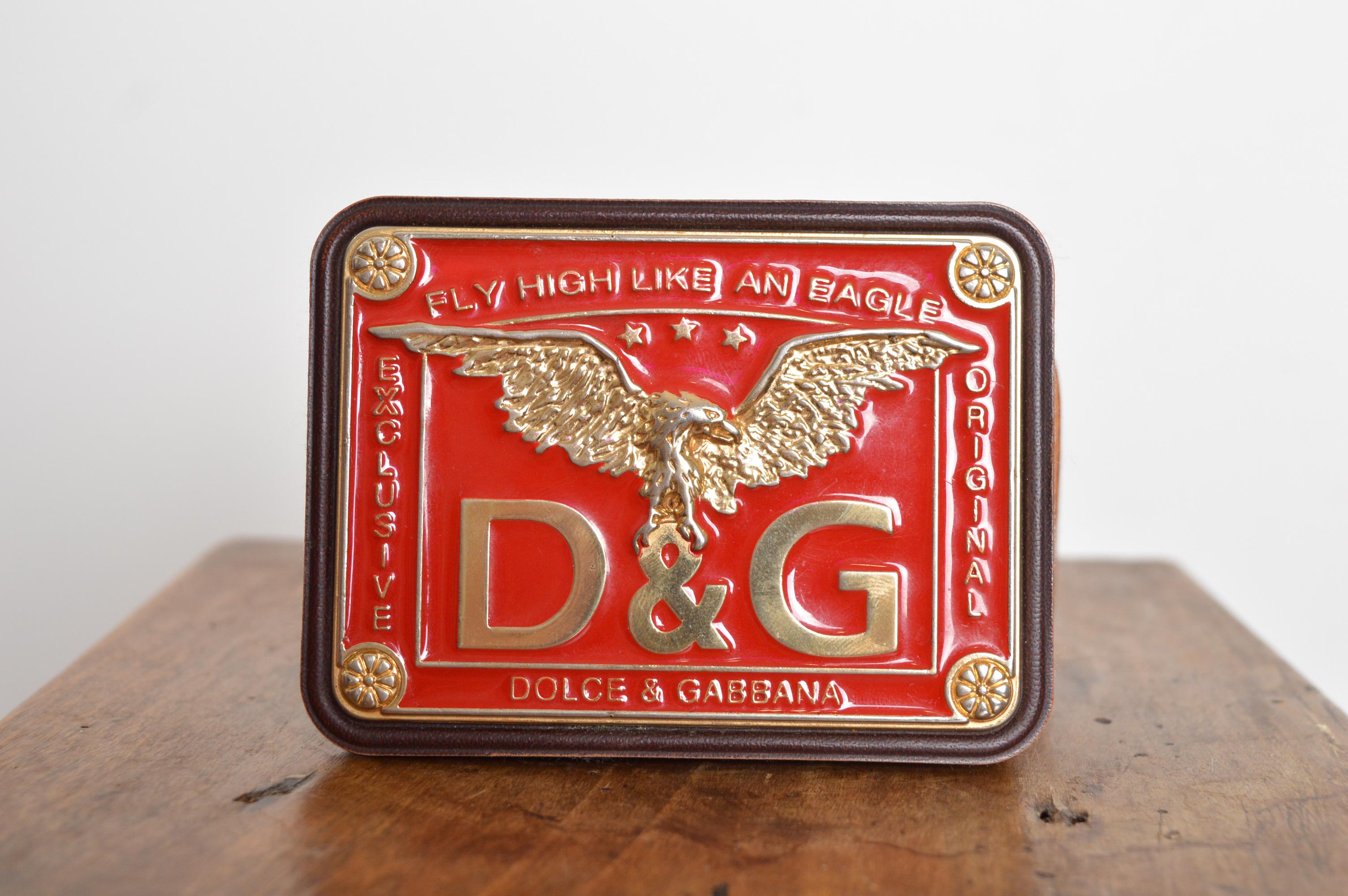 Cintura stile western/camionista Y2K di Dolce & Gabbana con grande fibbia smaltata rossa e logo decorativo dell'aquila.
Fibbia; 4 