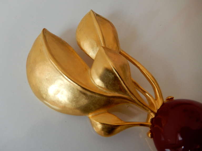 A large, witty resin brooch in the form of a dark red radish with gold-plated greens by Karl Lagerfeld, known for his innovative designs in jewelry and fashion.   Signed.