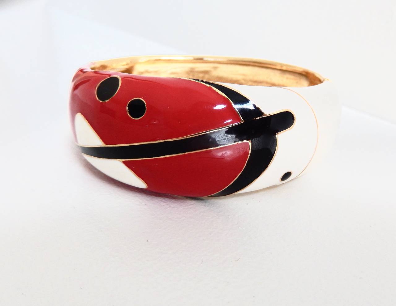 A vintage hinged cuff bracelet by Balenciaga with an enameled lacquer, abstract design.  Art Deco, Space-Age inspired graphics in bold colors--red, black and white. Marked:  Balenciaga Paris.  Very cool.

Comfortable fit for a smaller wrist,