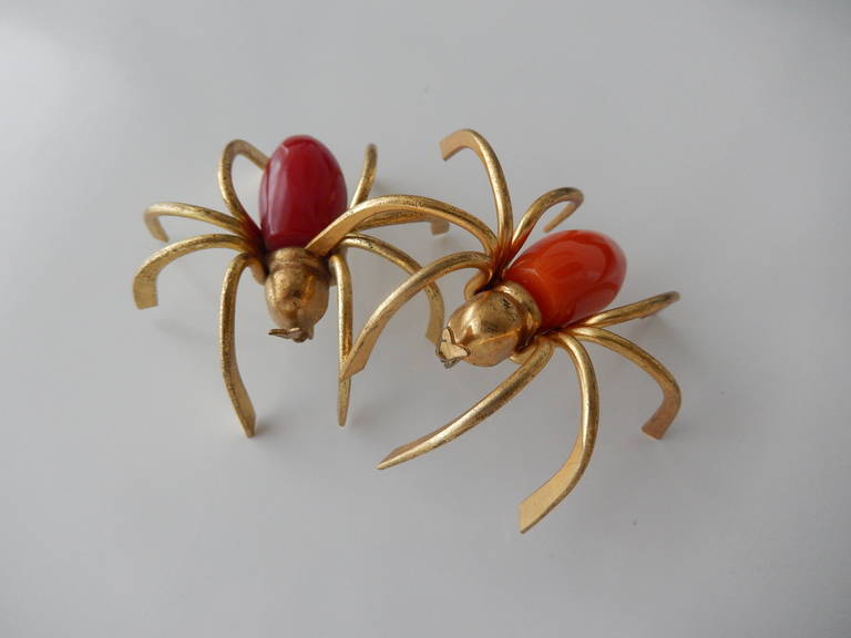 A pair of three-dimensional gilt metal spider pins with red and orange bakelite bodies.  The only spider pins one would want to wear.

Price is for the pair.