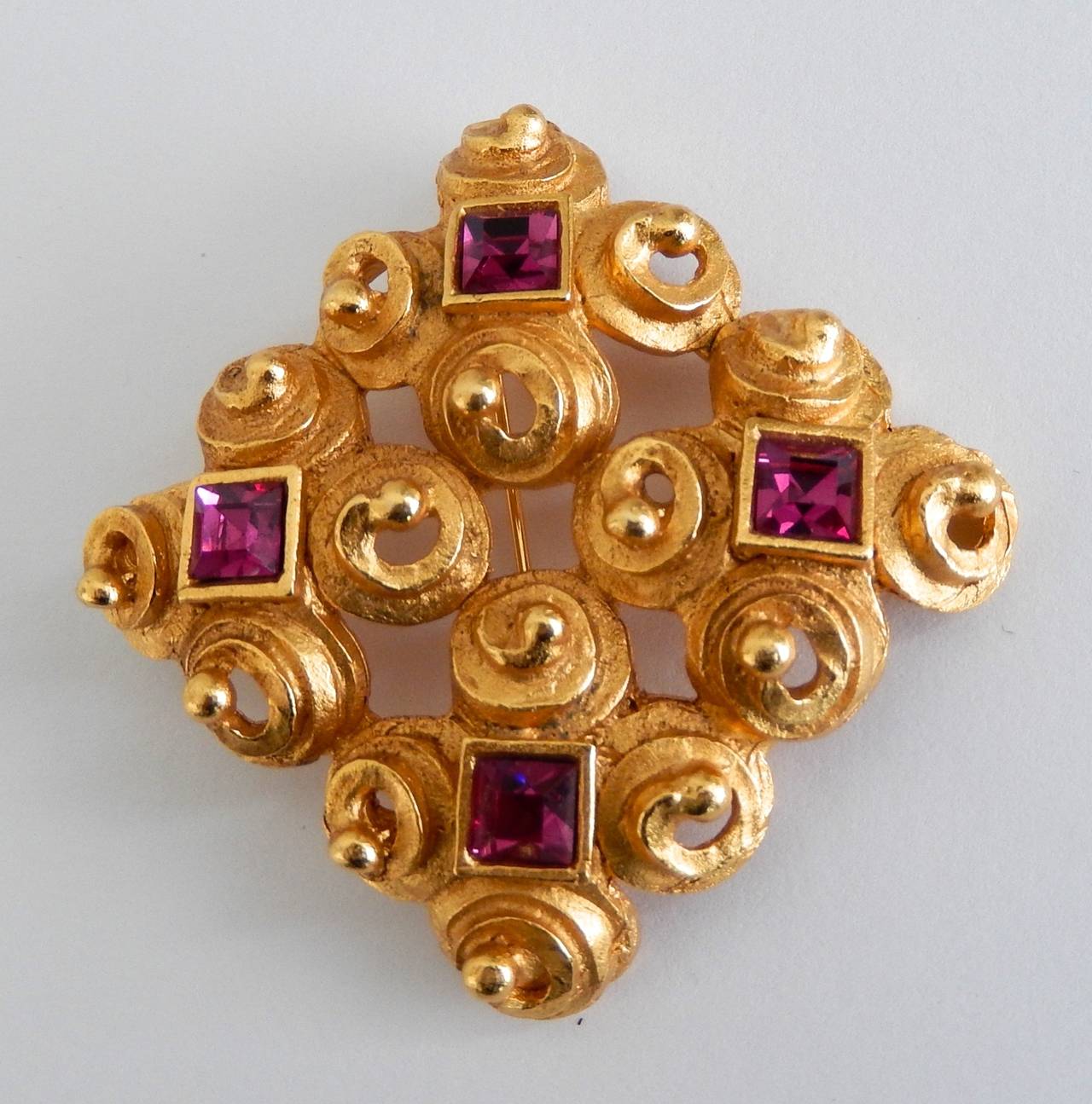 A gilt metal brooch with faceted synthetic rubies by Lanvin, Paris.
Graceful, interlocking spiral design with a rich, gilt metal patina. Beautifully made.  Marked:  LANVIN Paris