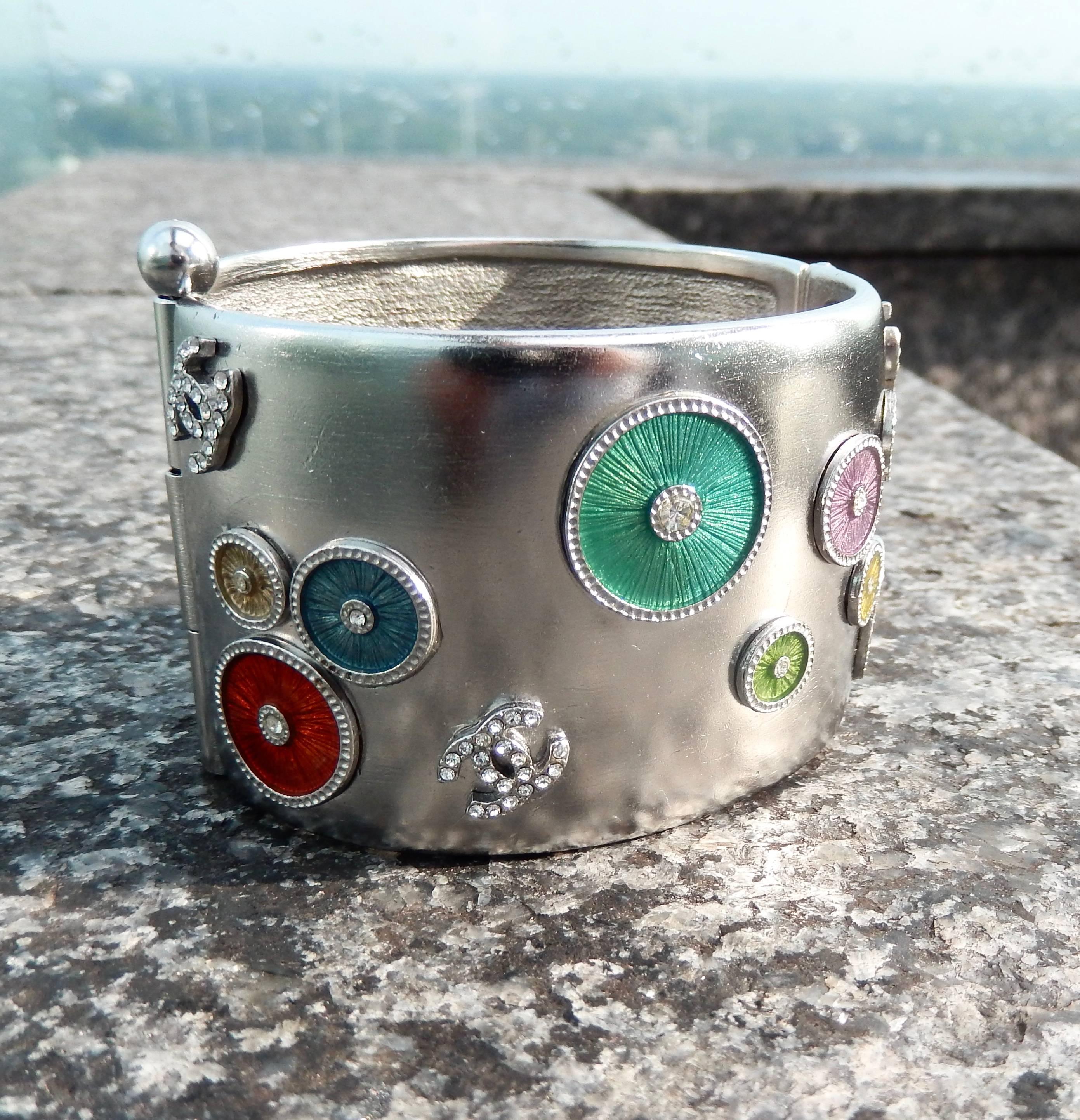A rare, silver-toned Chanel cuff from the 2002 Collection decorated with different-sized floating enameled circles. Suggests a Kandinsky-inspired design.  The colors are delicate and include lilac, orange, gold, blue and green.  The CC logo is also