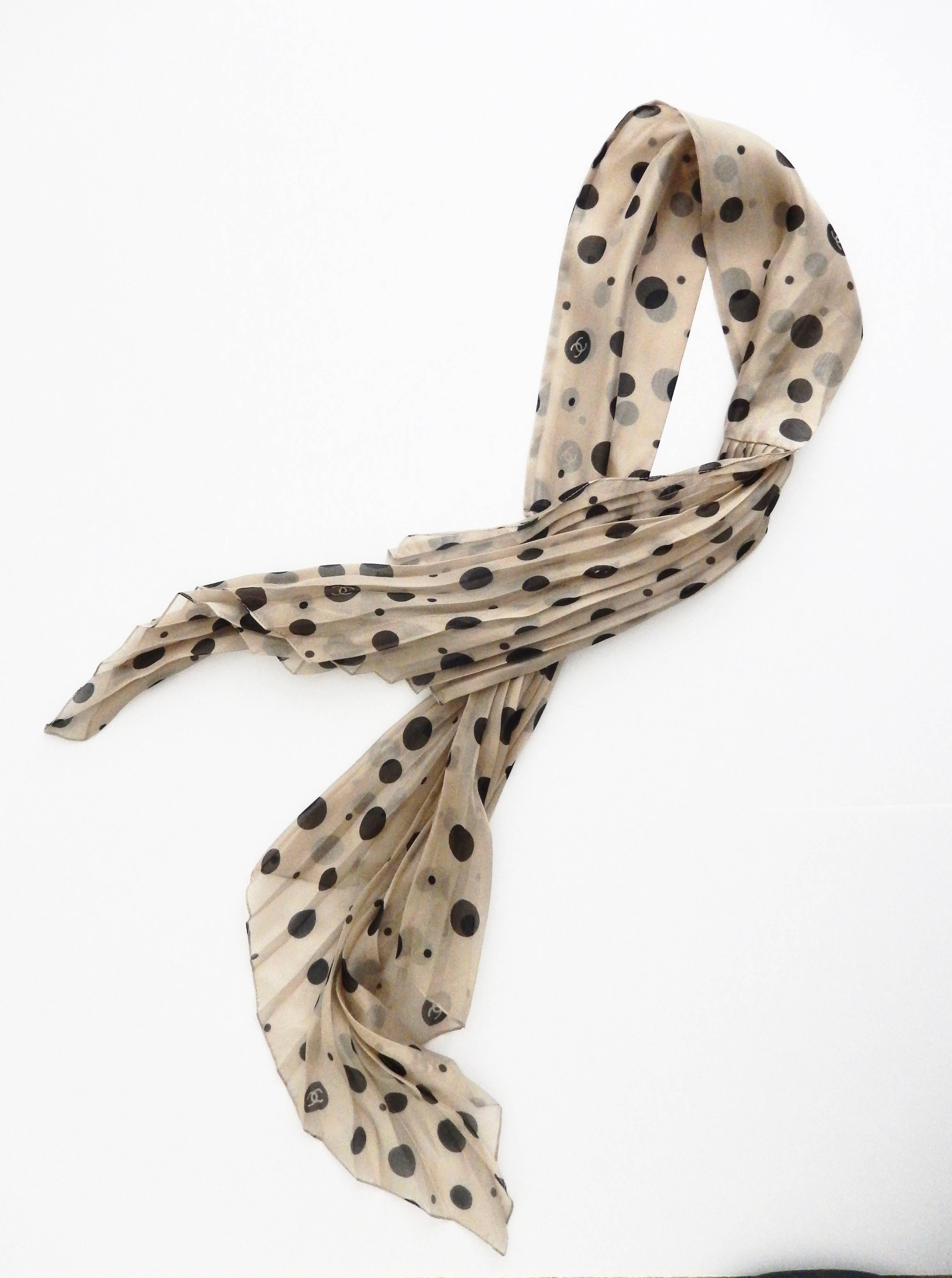 An elegant, vintage pleated scarf by Chanel in creme silk with black polka dots.  Chanel logo is incorporated into pattern.  The scarf has a delicate, subtle couture look and is very easy to wear.