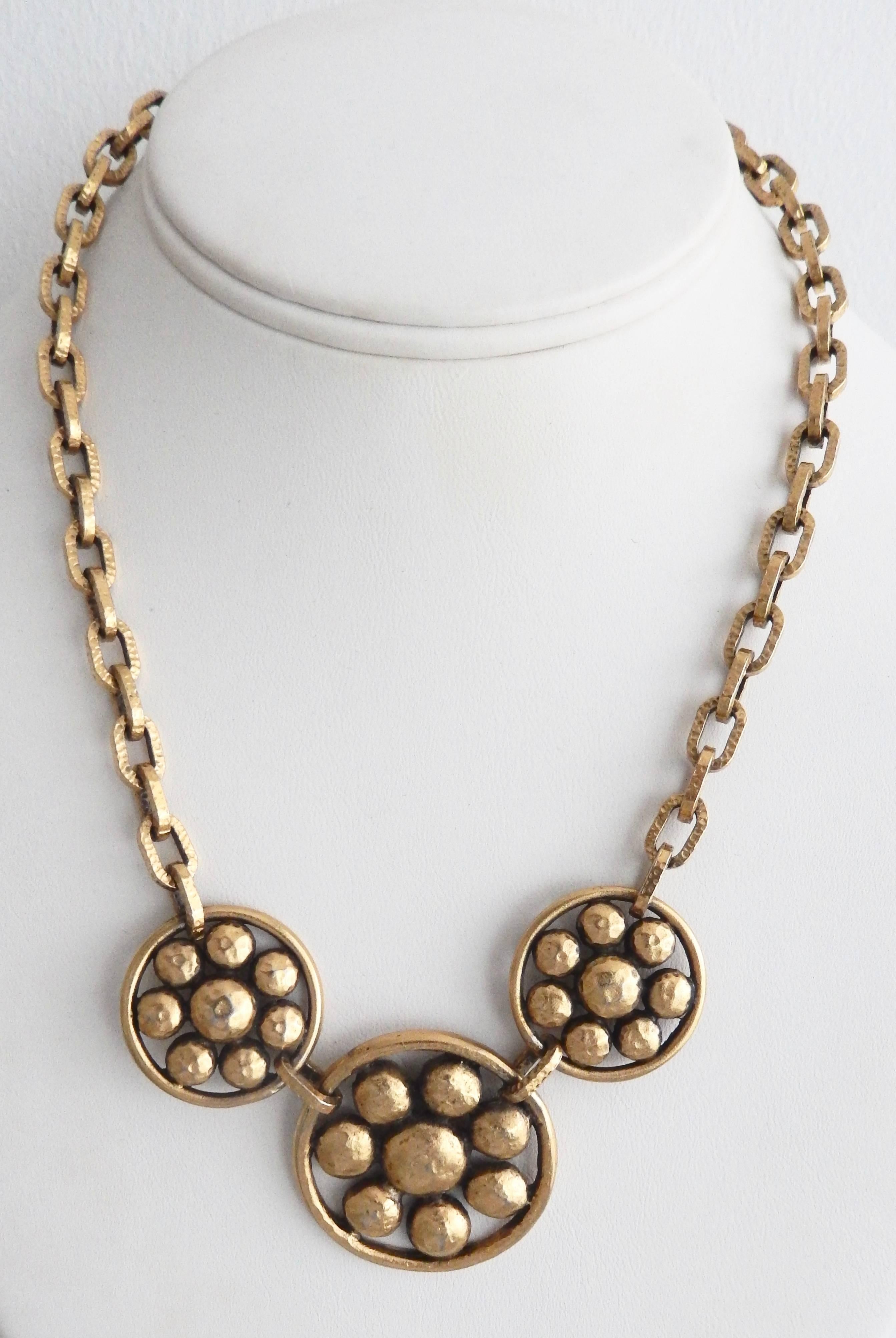 A sophisticated,  gold-toned necklace by Yves Saint Laurent with three stylized floral medallions.  Links have a beautiful, hand-hammered design and detailing.  Marked with inset YSL tag.

Diameter of central medallion:  1  1/2 in