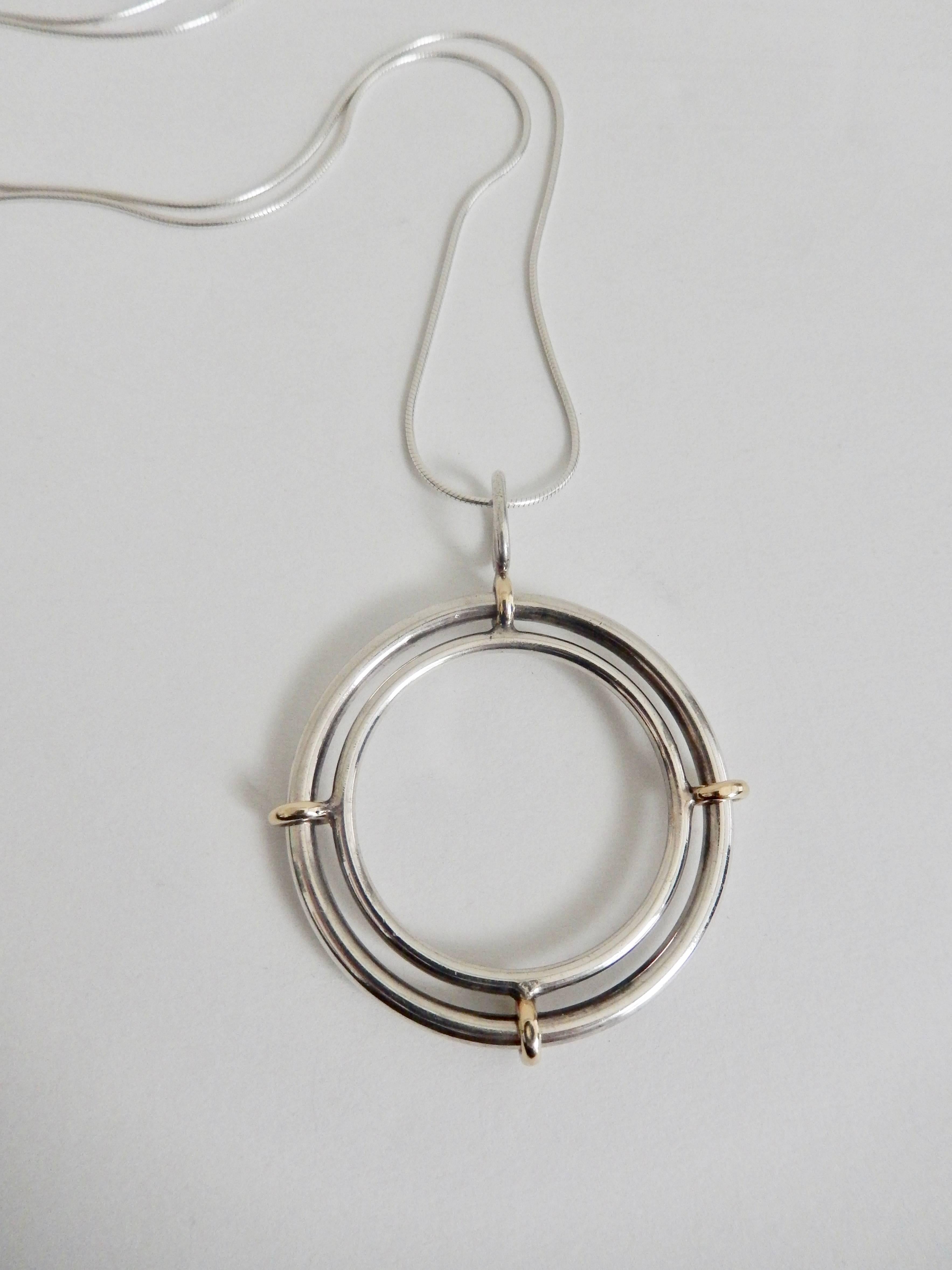 Inspired by the Space Age, a rare sterling and 14K gold pendant by Pierre Cardin (b. 1922) with a moveable outer ring.  Cardin's striking geometric design reflects a minimalist aesthetic, popular in the 1960s and 70s.  A collector's piece.  Signed: