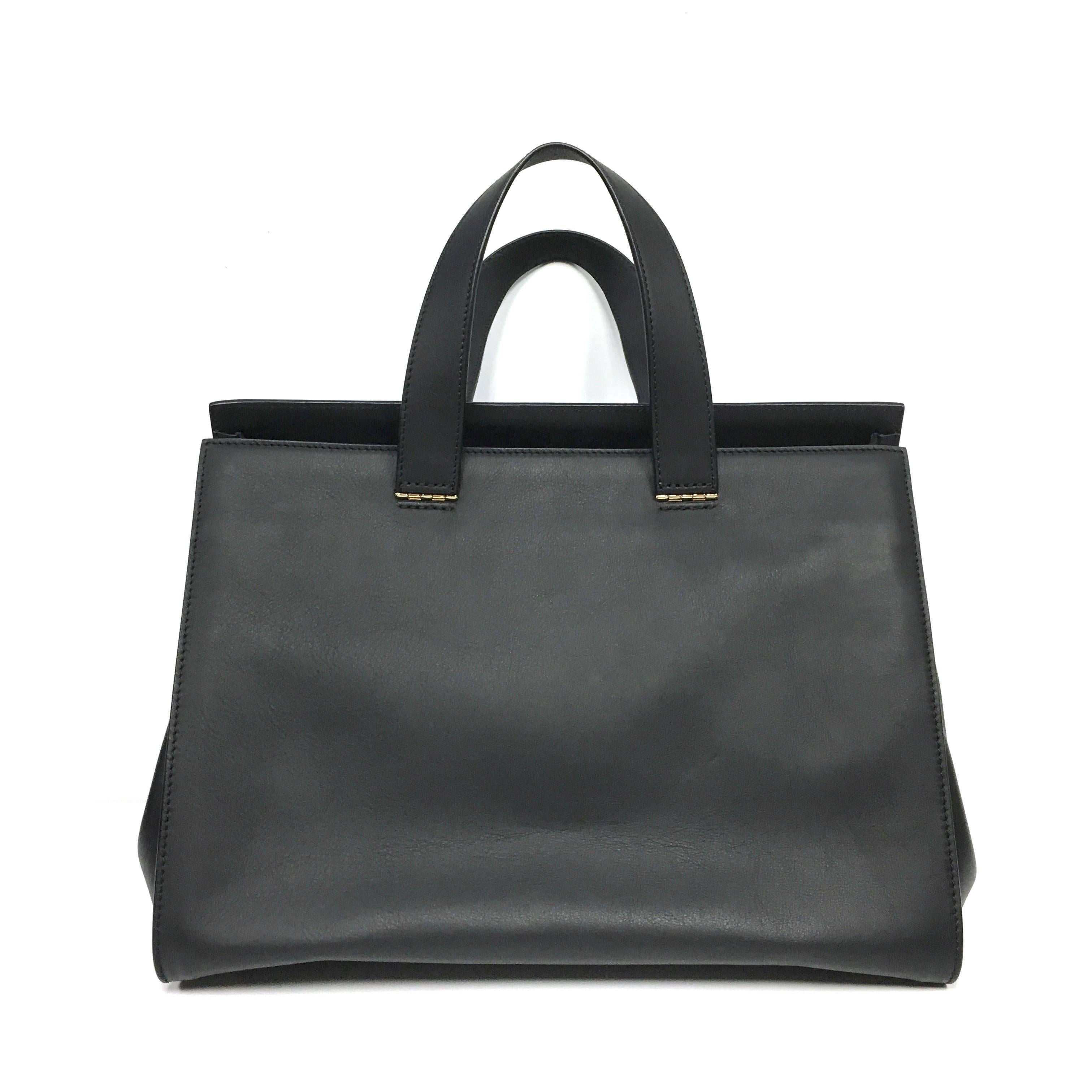 Black leather trapeze tote from Giorgio Armani featuring an embossed logo, top handles, gold-tone hardware, a magnetic fastening and an internal zipped pocket.  Composition: 100% Leather
Measurements:
Depth: 8.1 in
Handle drop: 6 in
Width: 14
