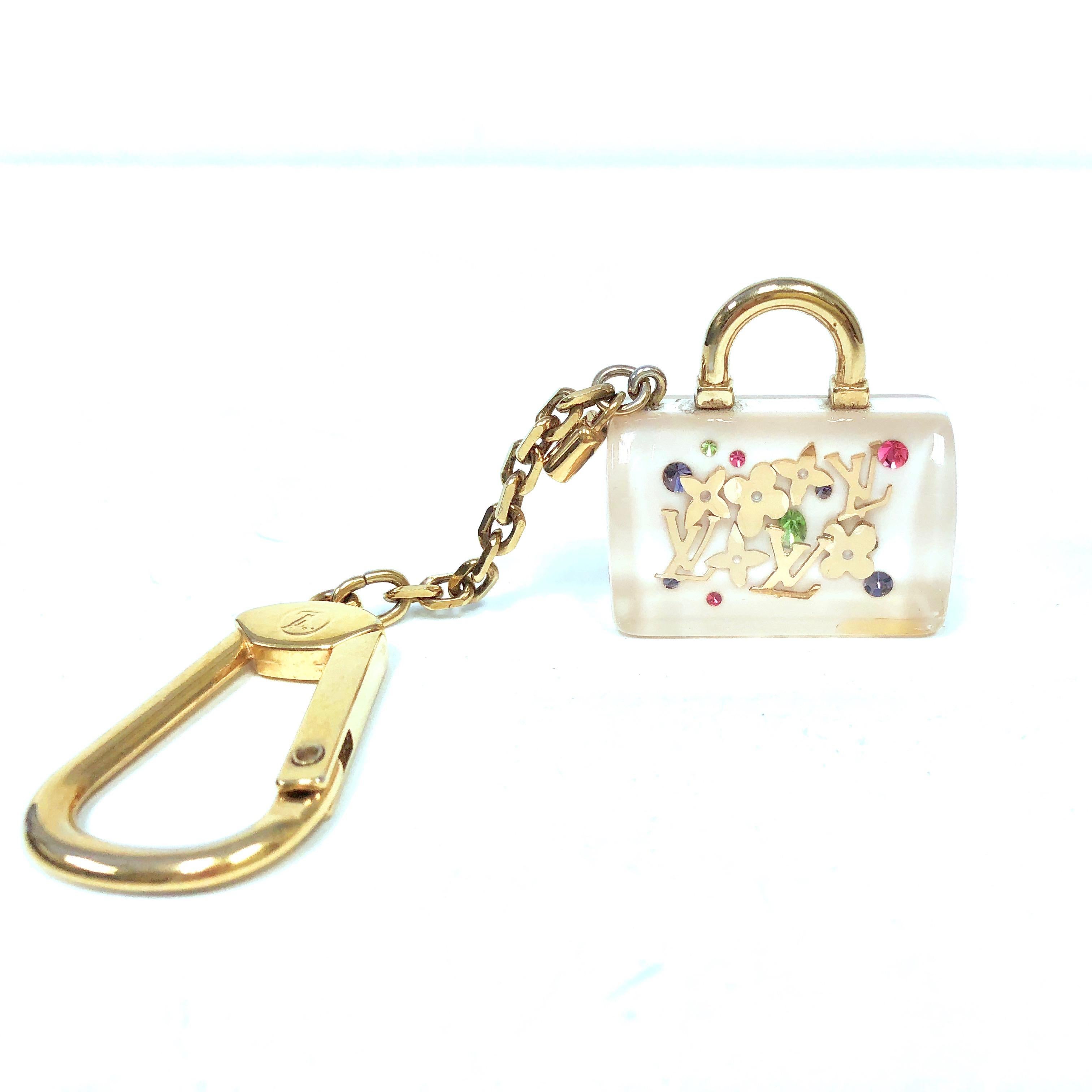 This Louis Vuitton white Speedy Inclusion charm features a white and clear resin Speedy bag with goldtone monogram logos and quatrefoils. The chain can be clipped on most metallic links on handbags or used as a key holder. 
Measurements: 4.5