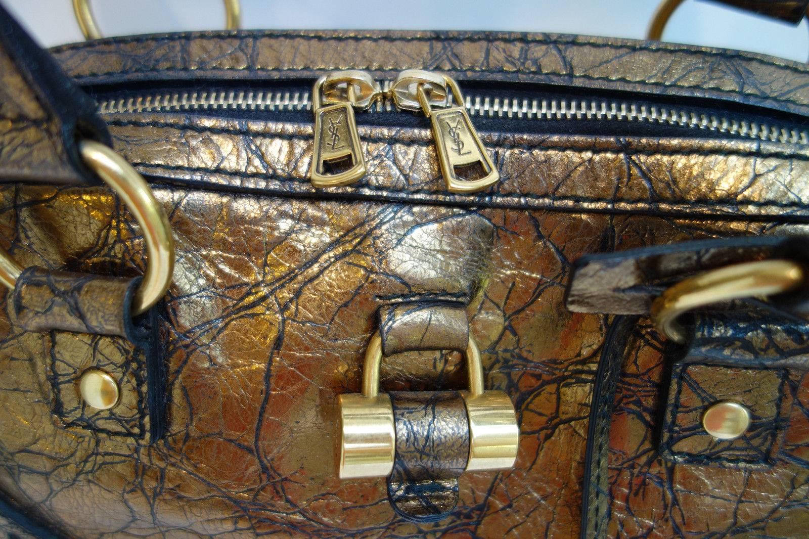 Bronze Distressed metallic leather with seamed stitch detail and logo imprint at front. Hard to find color, collectors piece. Absolutely stunning!
Antique gold tone padlock at front and ring detail at sides. Top two-way zip closure, leather straps