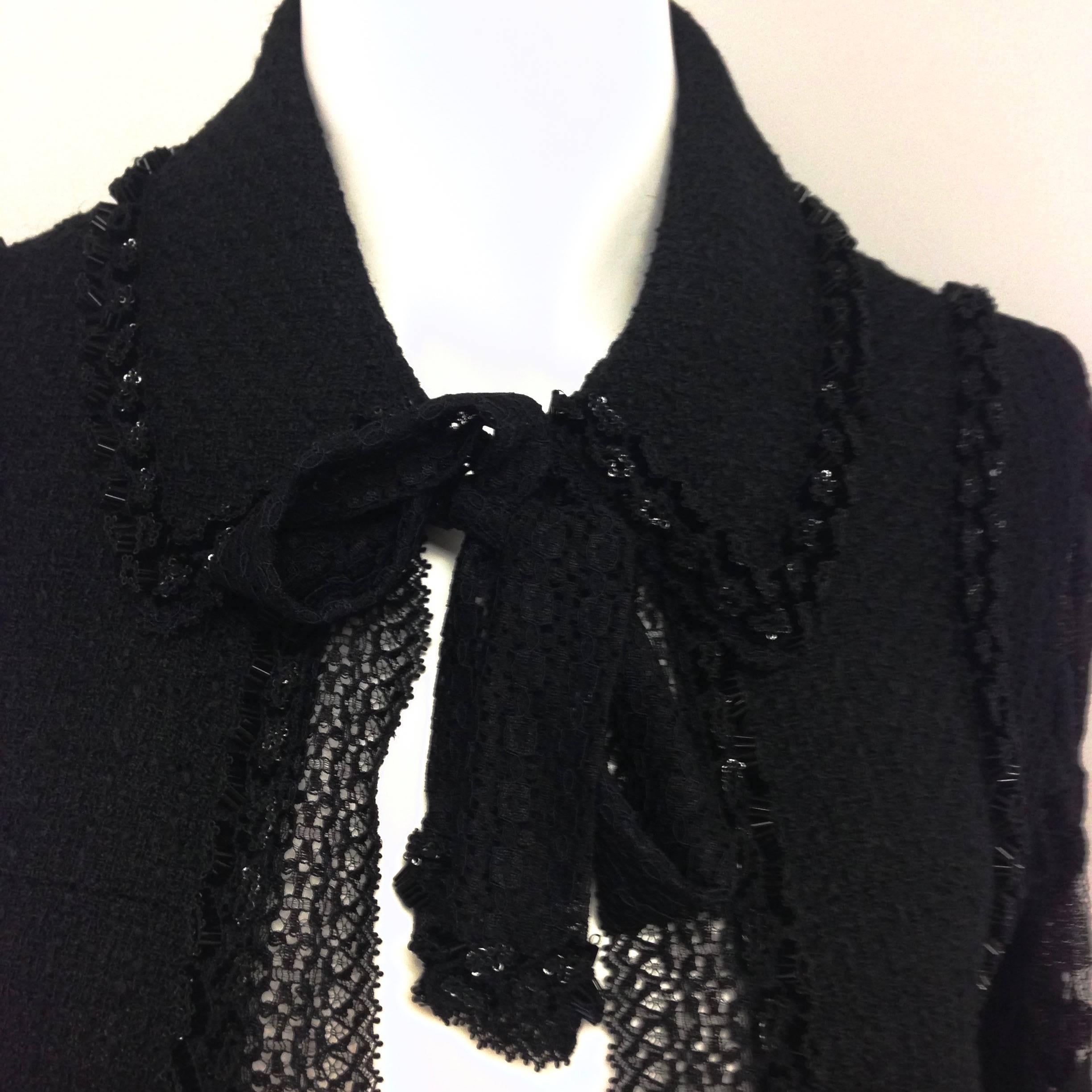 Authentic Chanel black tweed and lace beaded jacket. Features black beading detail, black lace full-length sleeves, two front pockets with button closures, and a tie detail at the neck. Composition: 99% wool, 1% nylon. Made in France.
Size: 38 