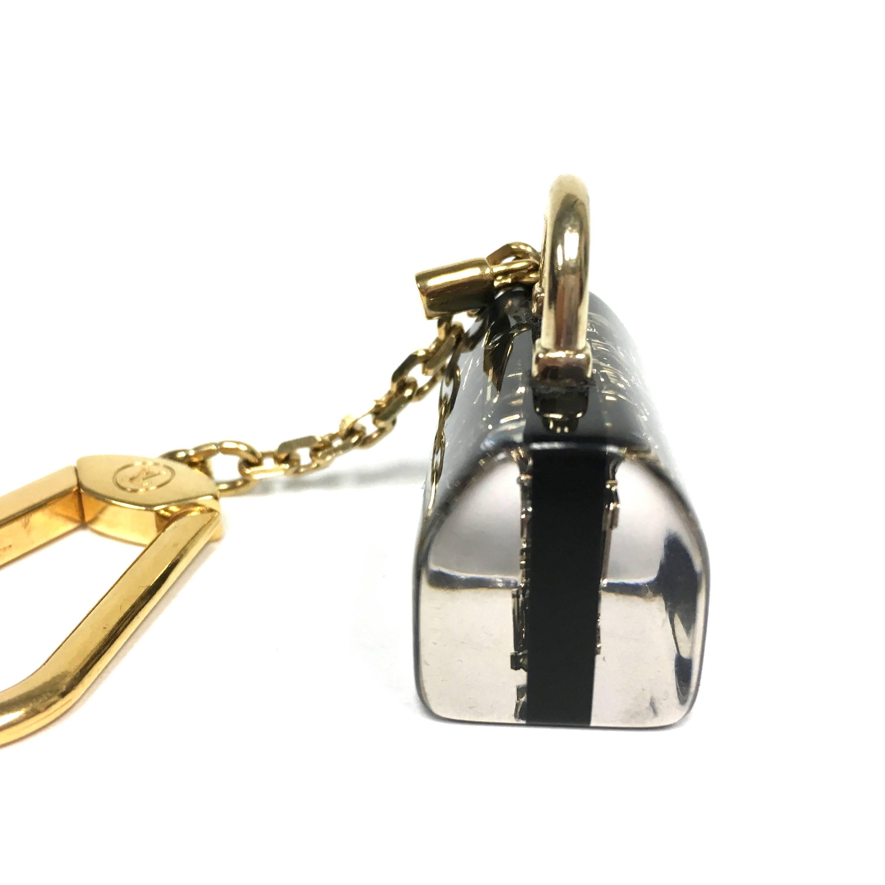 LOUIS VUITTON Inclusion Black and Gold Speedy Bag Charm. 
This chic key chain is composed of a black and clear resin Speedy charm with a gold snap hook and chain. The charm is embellished with gold monogram symbols and assorted crystals.