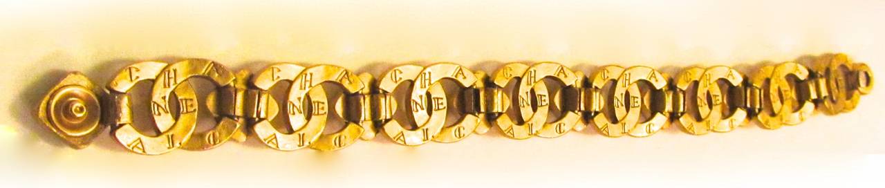 Vintage Chanel gold toned bracelet with gripoix stone inlay. Stone colors are amber, red, and blue. Snap closure. Chanel CC logo is embossed on the bracelet and name is inscribed on the gold metal of the band throughout. Links on the gold band are