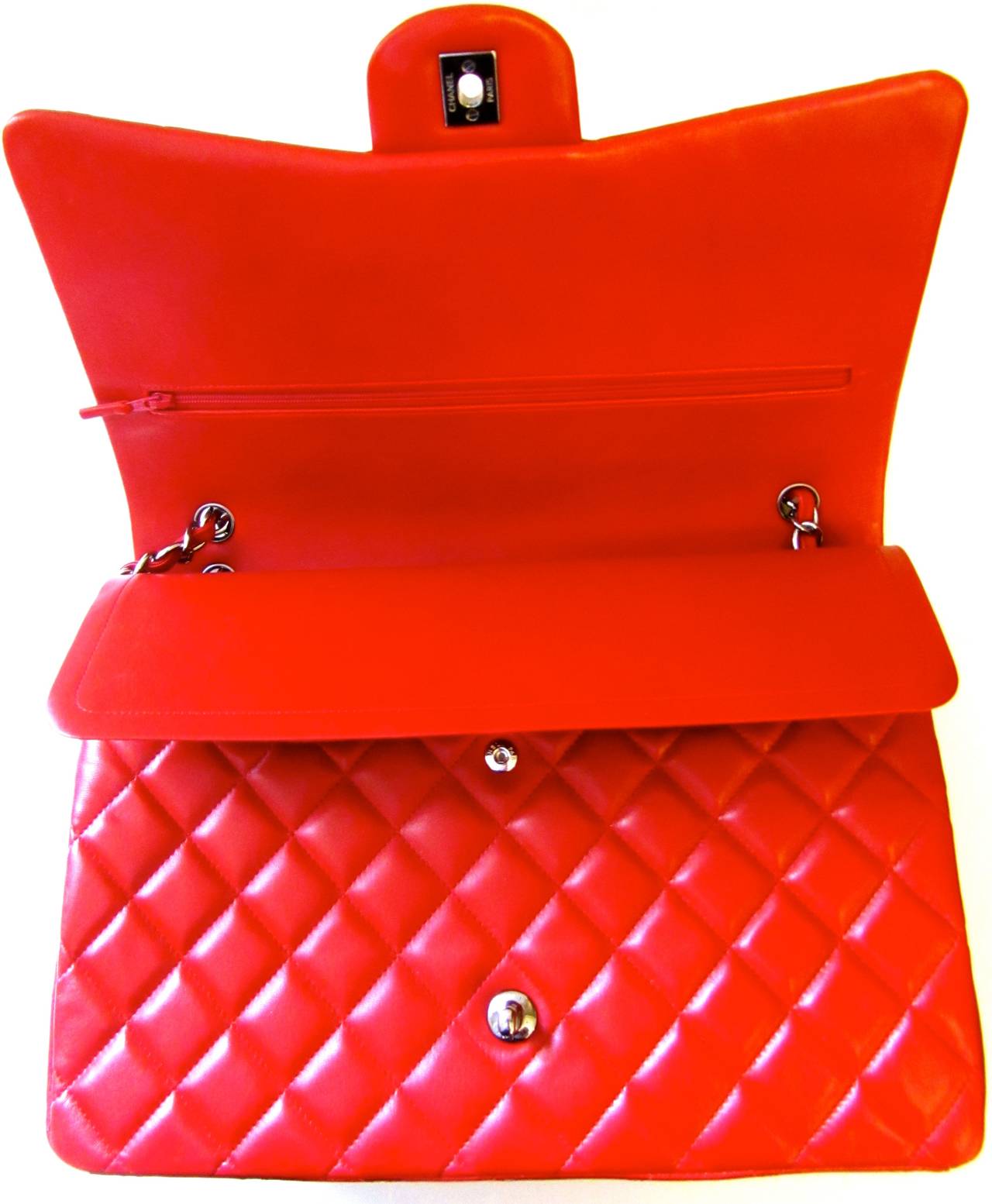 New Chanel classic double flap maxi hand bag in red. Gorgeous lambskin with classic Chanel chain for handle. Titanium colored hardware. Snap close on interior pocket. 

Remarkable bag for any occasion in a highly sought after color. Gorgeous bag