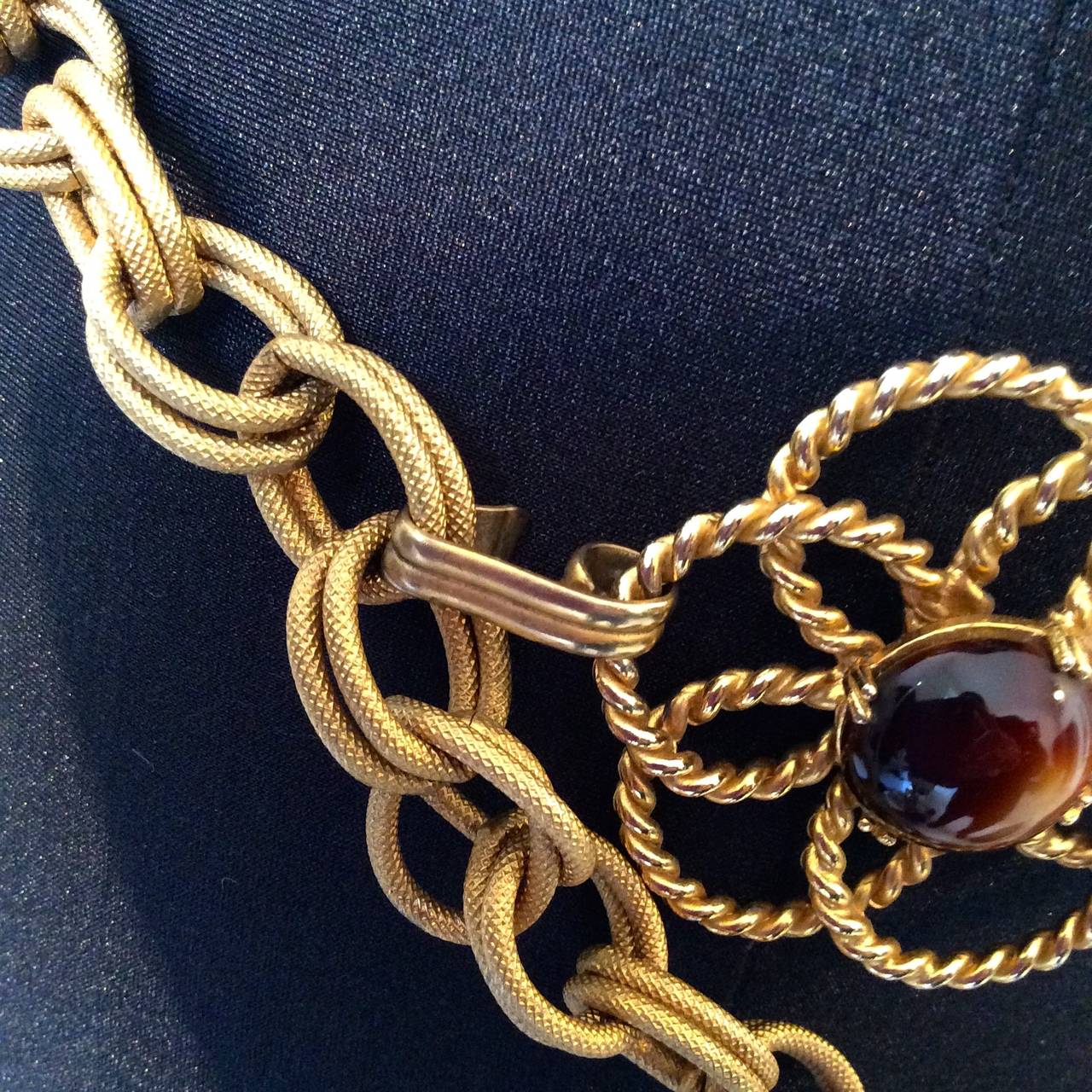 Rare 1970's Yves Saint Laurent Belt with amber colored cabochon stones with pearlescent tone. Belt is adjustable for varying sizes but entire length of built is 44 inches. Floral design with matte finish gold tone. Hook close for belt.