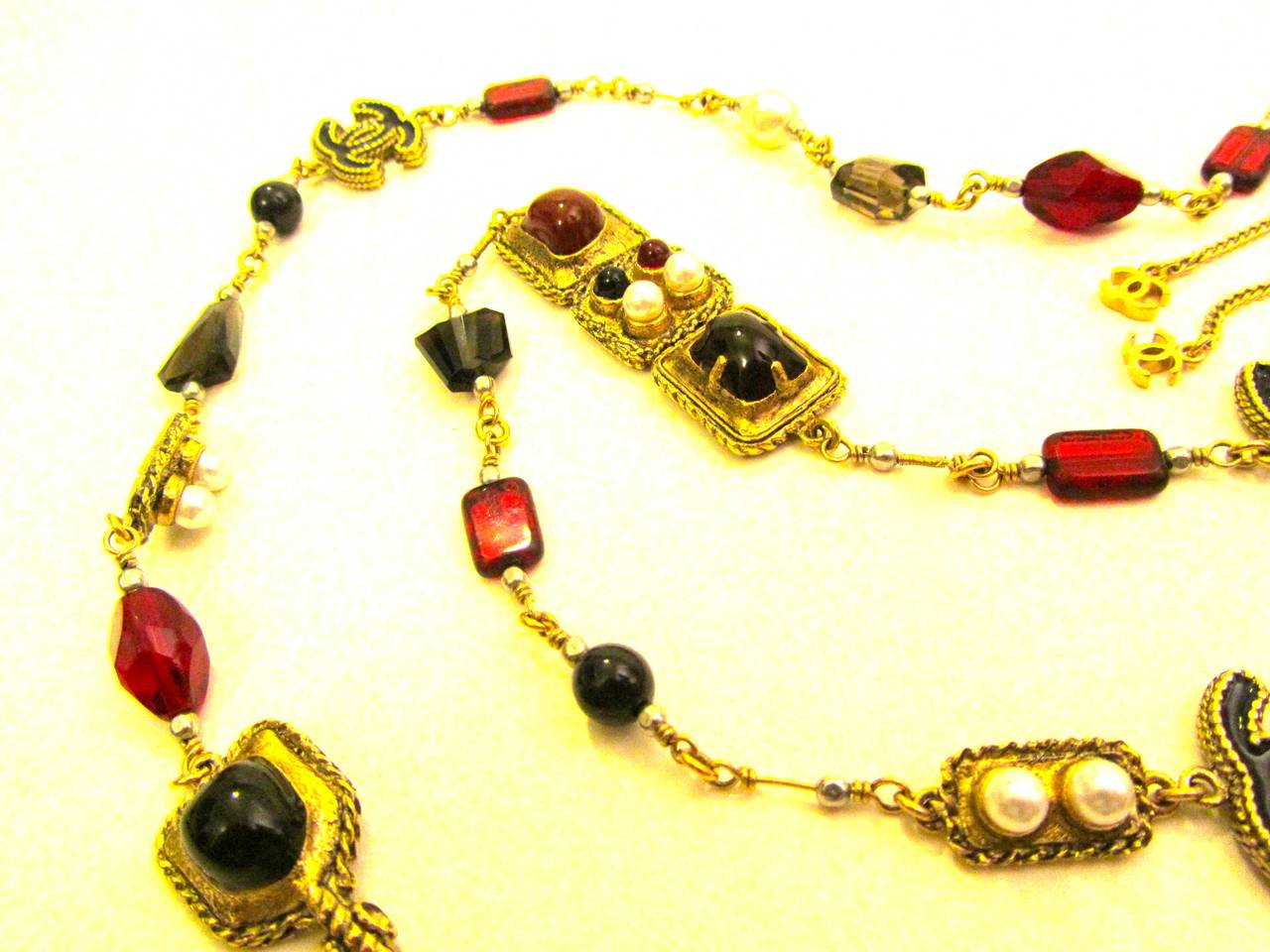 New Chanel necklace. Gold tone chain with faux pearls and alternating ornate gripoix stone inlay. Red, black, and gray gripoix stones. Black and gold CC logos on necklace. Rare and gorgeous necklace that is versatile for various occasions.