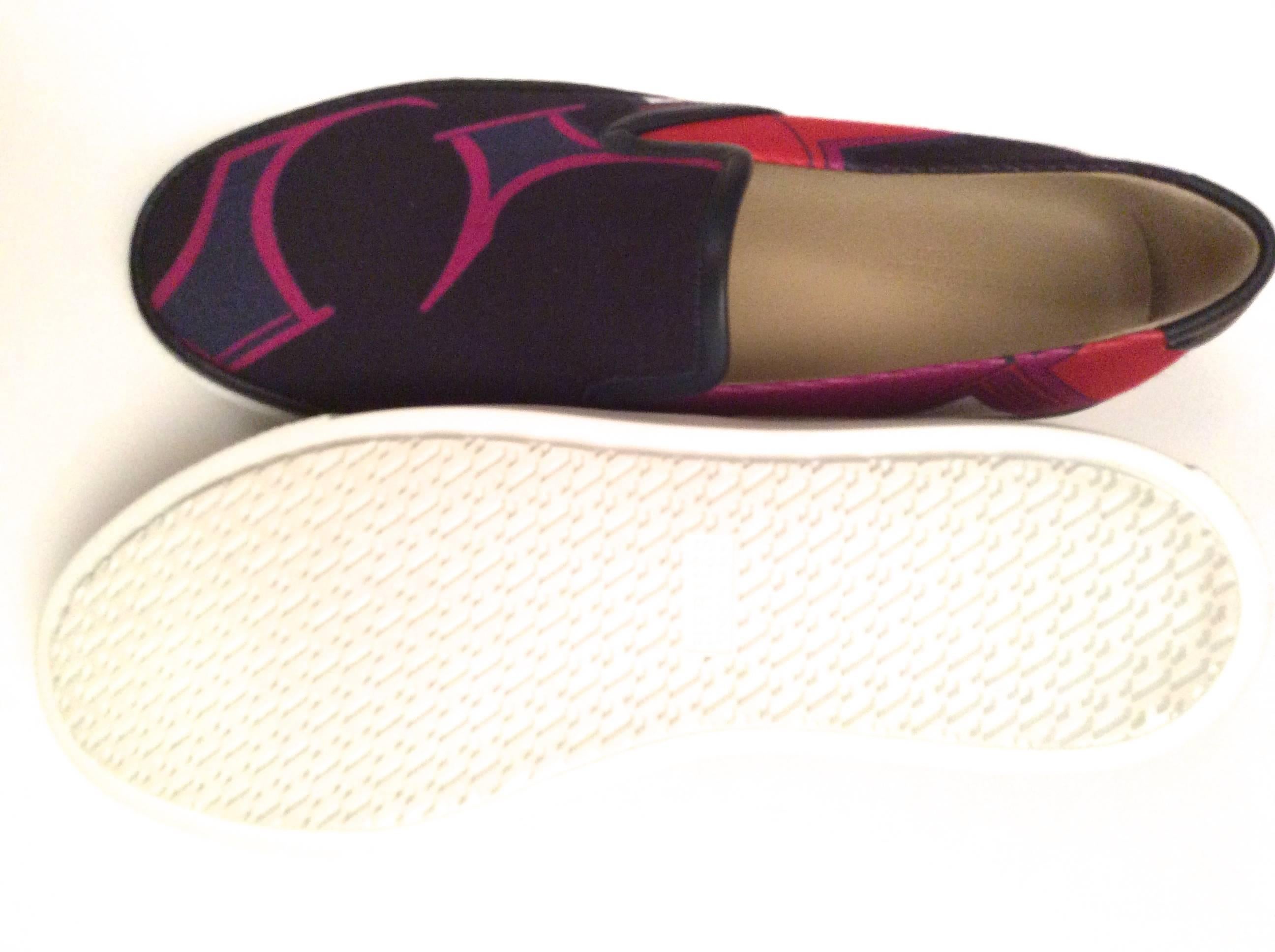 These new women's Hermes sneakers are a size 38. They are cloth, lined in leather, and have rubber bottoms. They have a unique blue, purple, red and pink geometric design. They are a size 38 and run a little big. There is blue leather border around