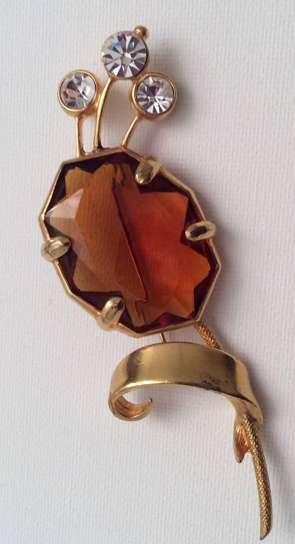 Presented here is a Christian Dior brooch pin from the 1960's. The pin is made out of gold tone metal and has 3 white rhinestones and one large amber colored glass gem. A great example of Dior's costume jewelry design. Very nicely crafted and