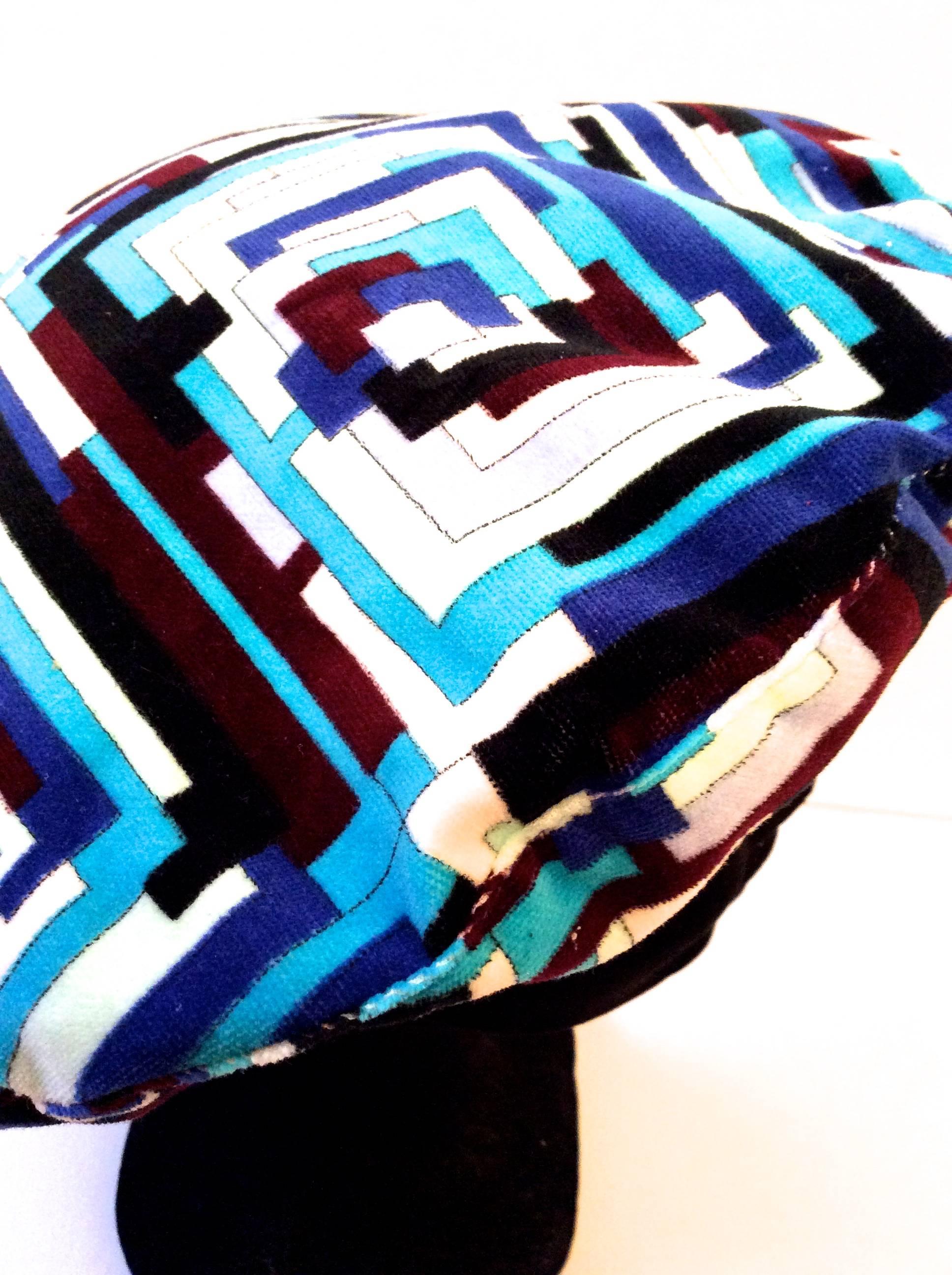 This Emilio Pucci beret is a gorgeous blend of shades of blue, white, black, and maroon. It is a gorgeous geometric rectangular design and is made of 100% cotton with a velvety textured fabric on the exterior. The beret is lined with a blend of 60%