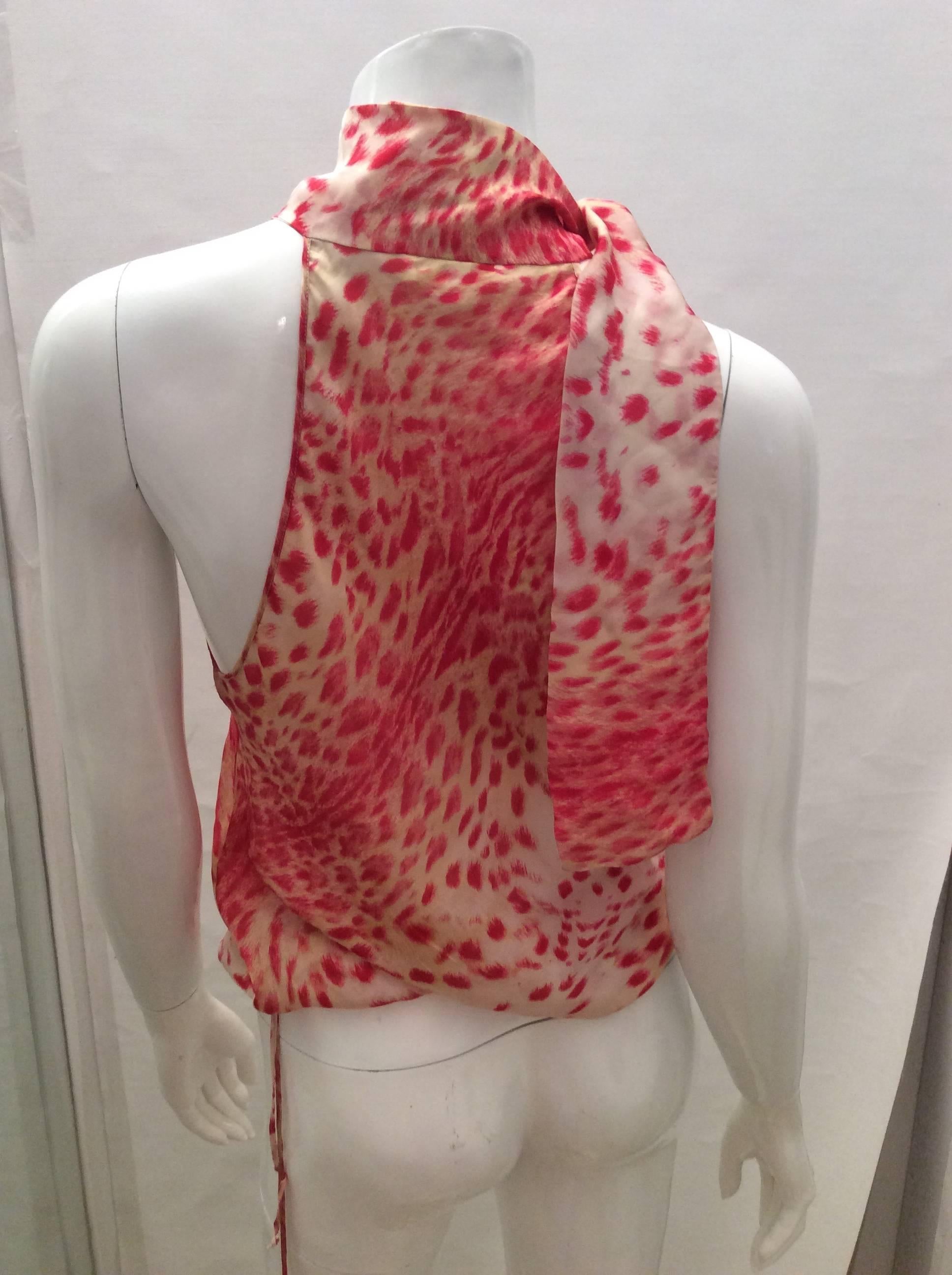 Presented here is a sexy halter top from Roberto Cavalli. The top is made of silk. It is comprised of a design of a white background with intriguing geometric spots throughout the core of the design. The top is sleeveless. There is a tie at the back