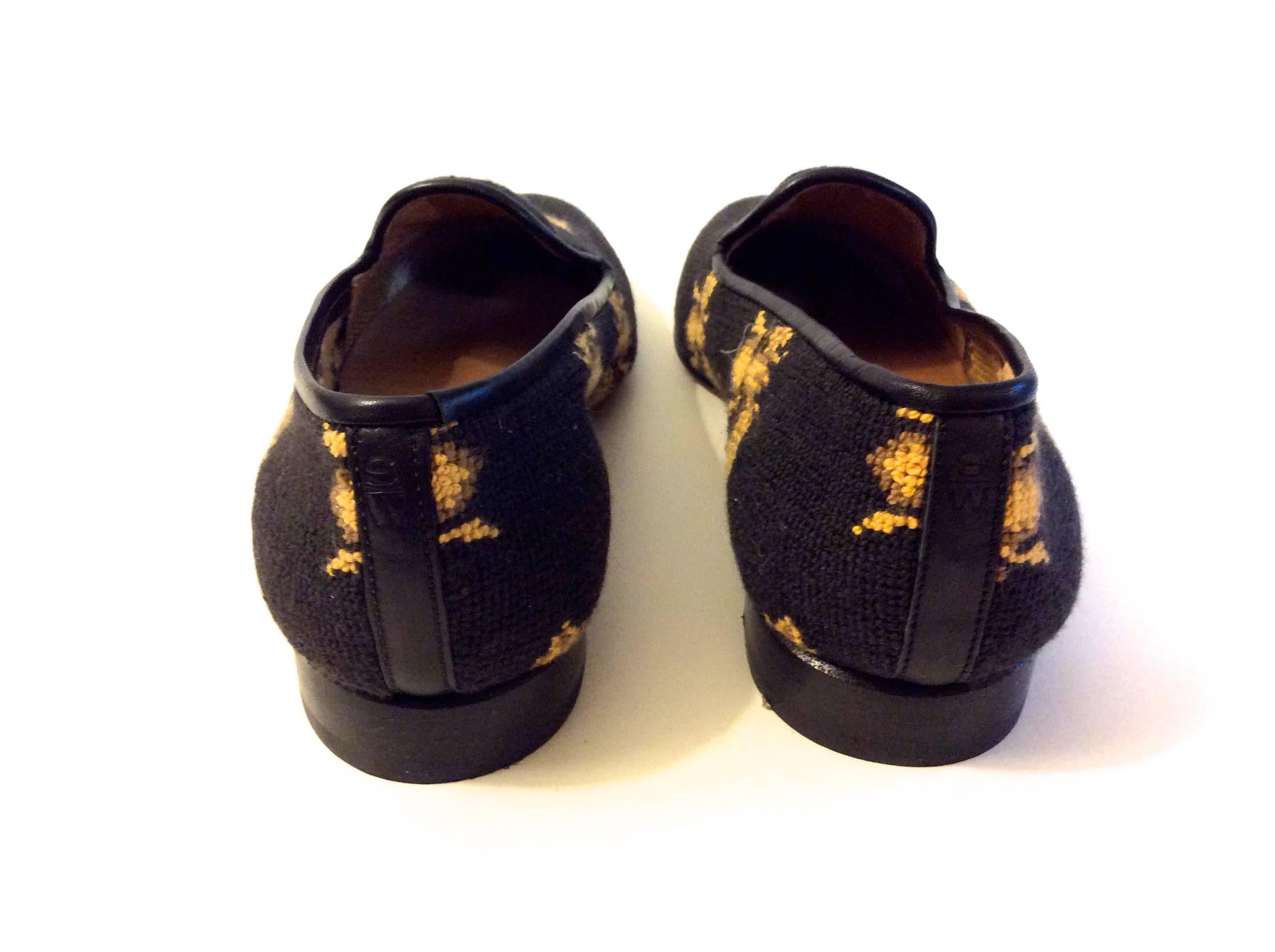 This new pair of Stubbs and Wooton of Palm Beach shoes is a size 7.5. They are made in Spain and are a needlepoint stitching throughout the body of the shoe. The sole is made of leather. There is a golden image of a bud sewn throughout the body of