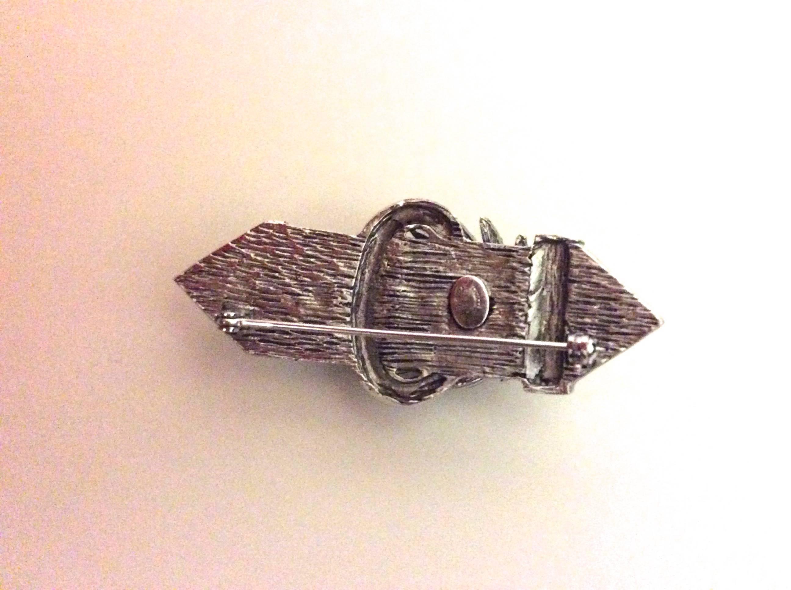 Presented here is a rare brooch from designer Hattie Carnegie. The brooch is from the 1950's. The brooch is a brushed silver tone metal that measures 2 inches long and .5 inches high and can be worn upwards or sideways. The beautiful cascading