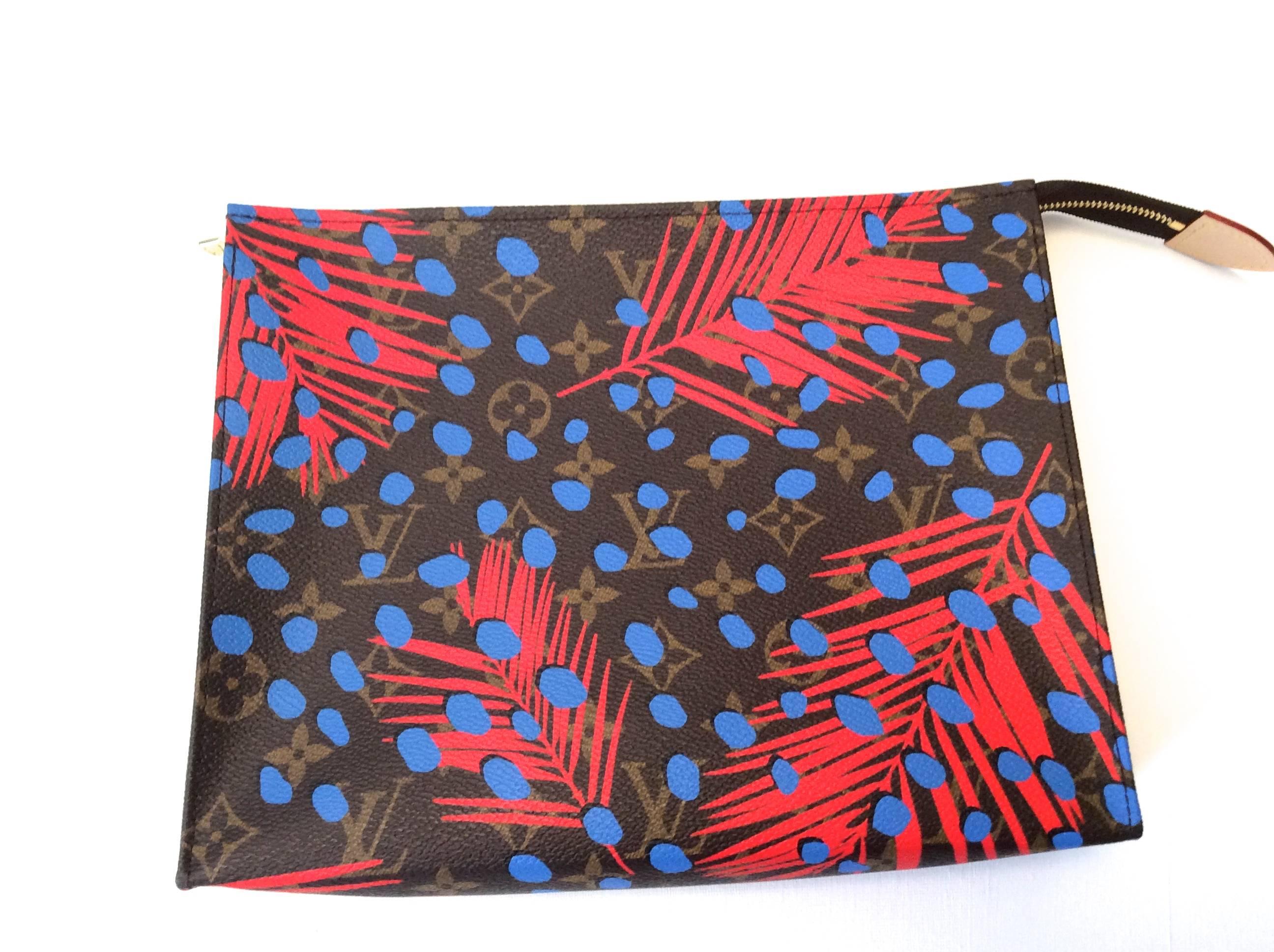 This Louis Vuitton Palm Springs Pochette Etoile clutch bag has the classic Louis Vuitton brown print with graphics of red leaves and blue dots on the exterior of the bag. The interior of the handbag is red. 

This bag is a limited edition that is