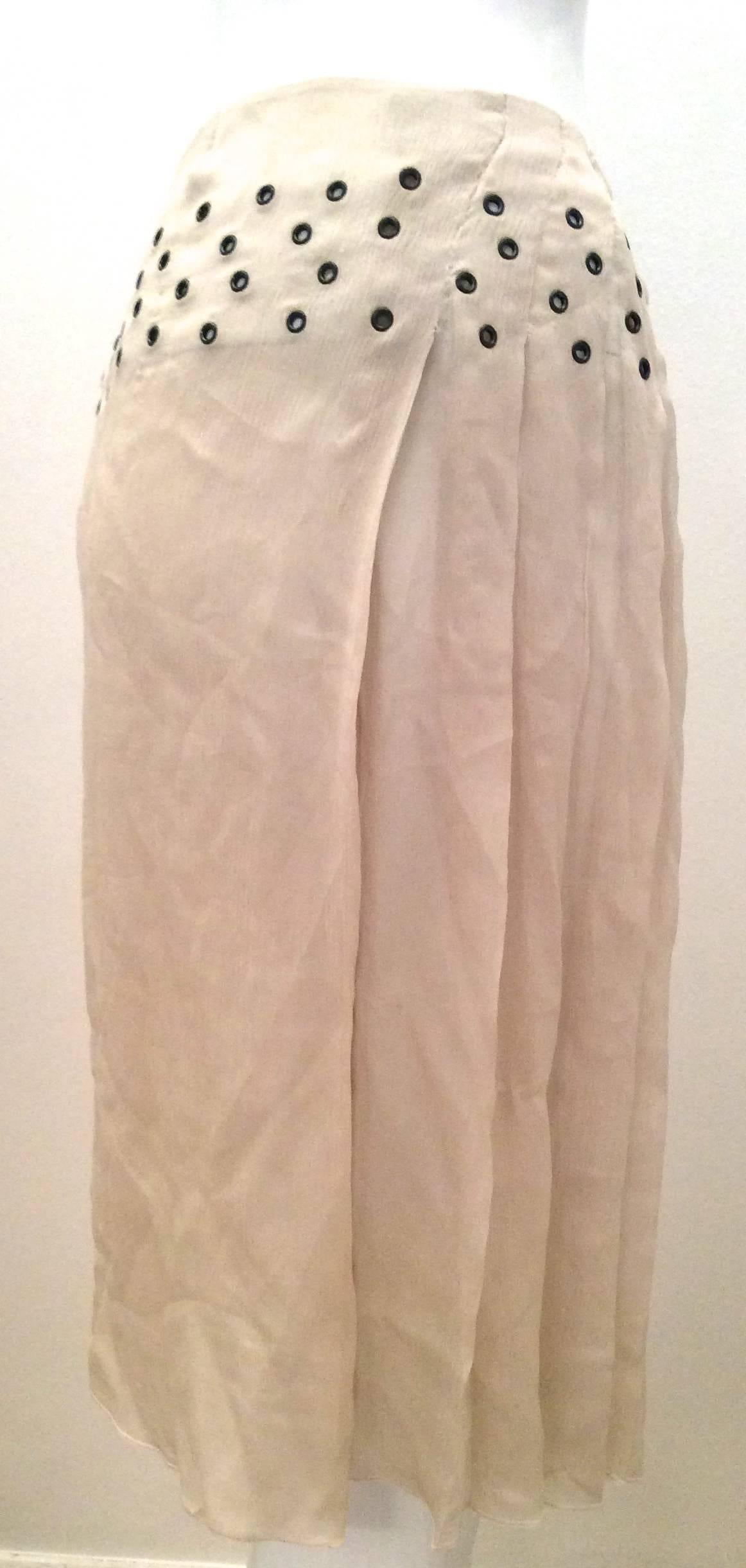 Presented here is a silk Prada skirt that is a creamy beige color. The skirt is made of 100% silk sheer fabric. There are grommets around the top of the skirt from about 1.5 inches from the top of the waist to 4 inches below the waist of the skirt.