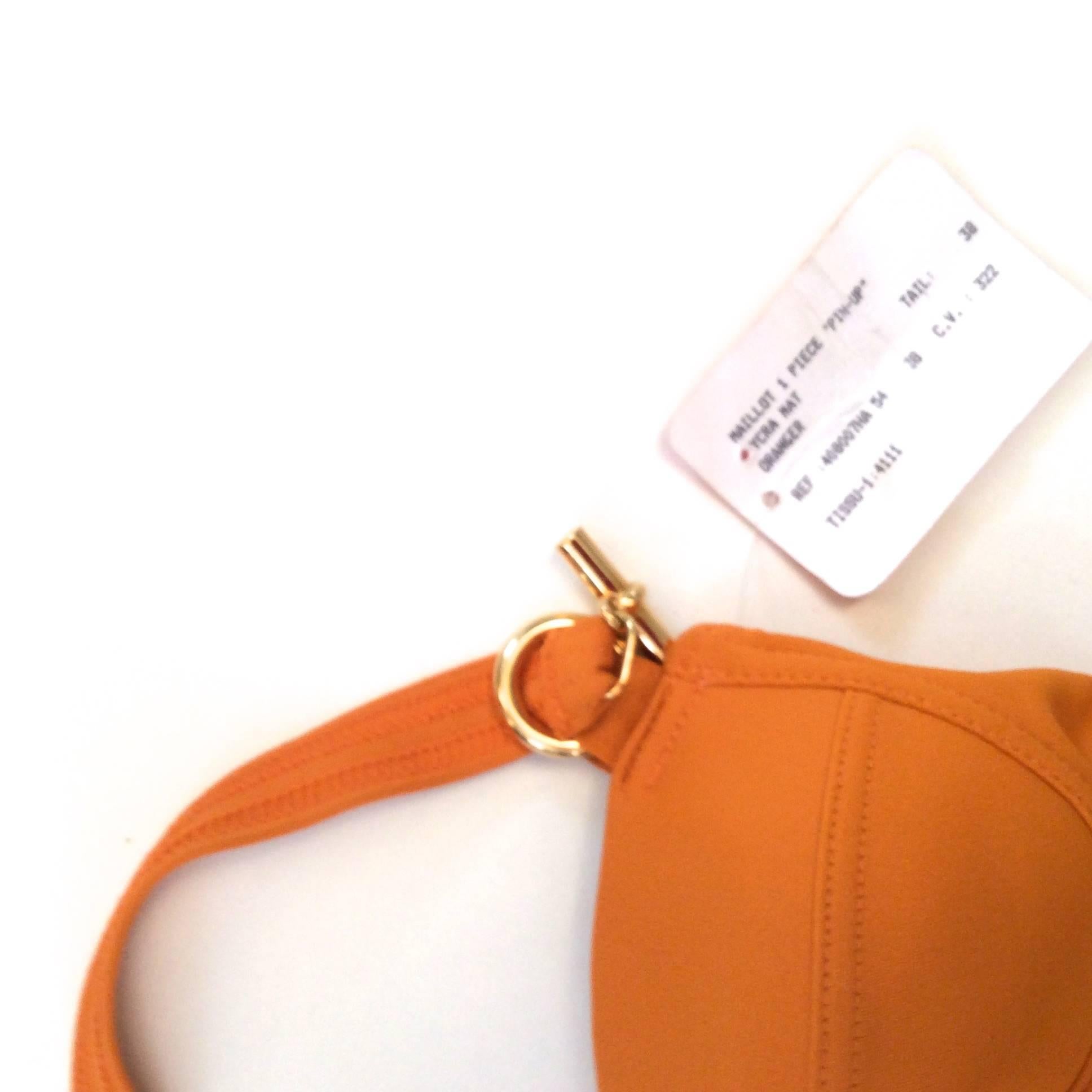 Presented here is a beautiful orange, new, size 38 Hermes bathing suit. Beautiful bathing suit is 88% nylon and 12% lycra. It has an incredibly strong and flattering fit. This one piece suit encompasses a single strap which goes around the top of
