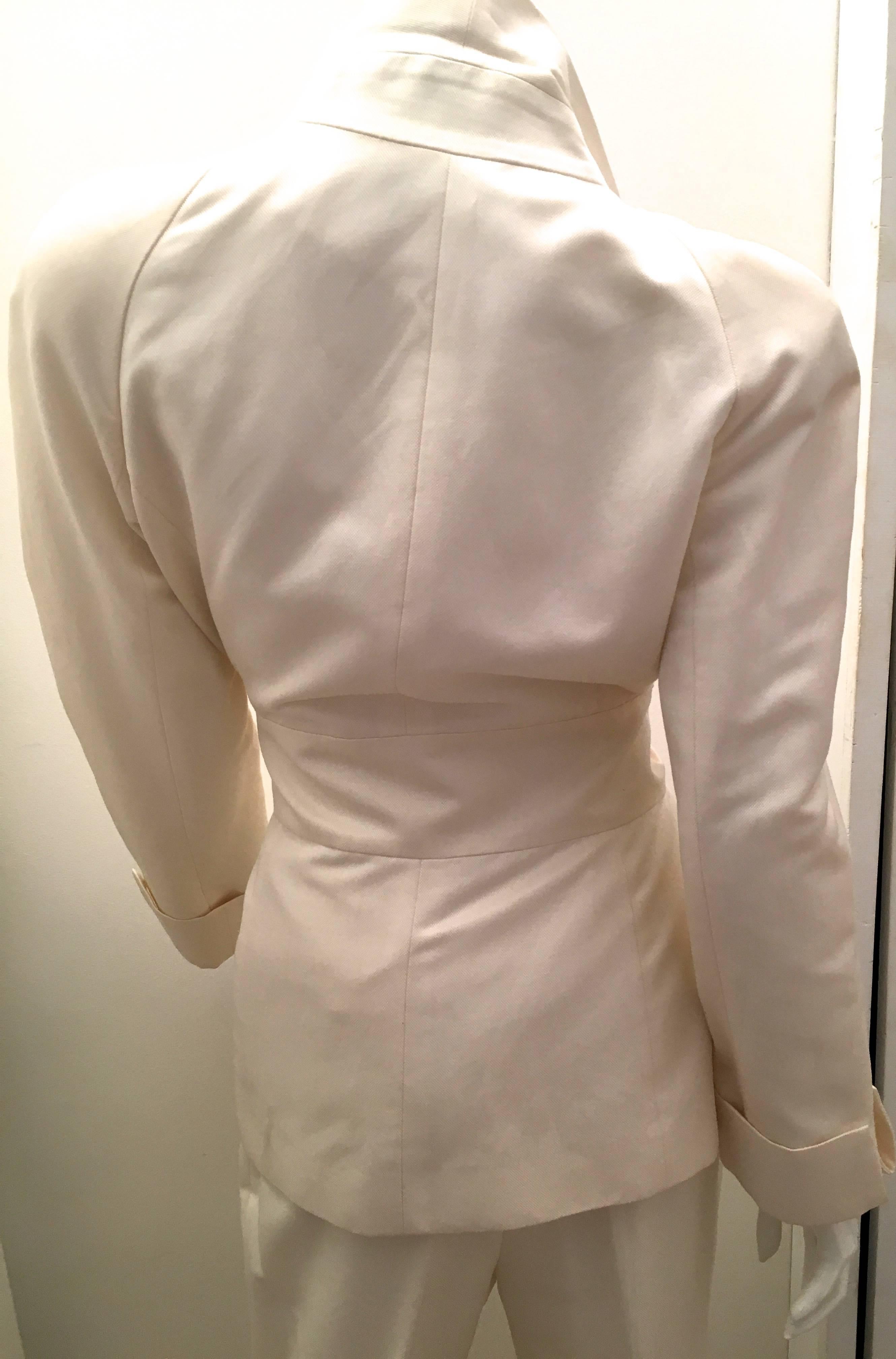 Presented here is a stunning suit from Jean-Louis Scherrer. The suit is a gorgeous white cotton and silk blended fabric entirely lined with white silk and it appears to have  been worn perhaps once or twice. The suit has a connected white belt tie
