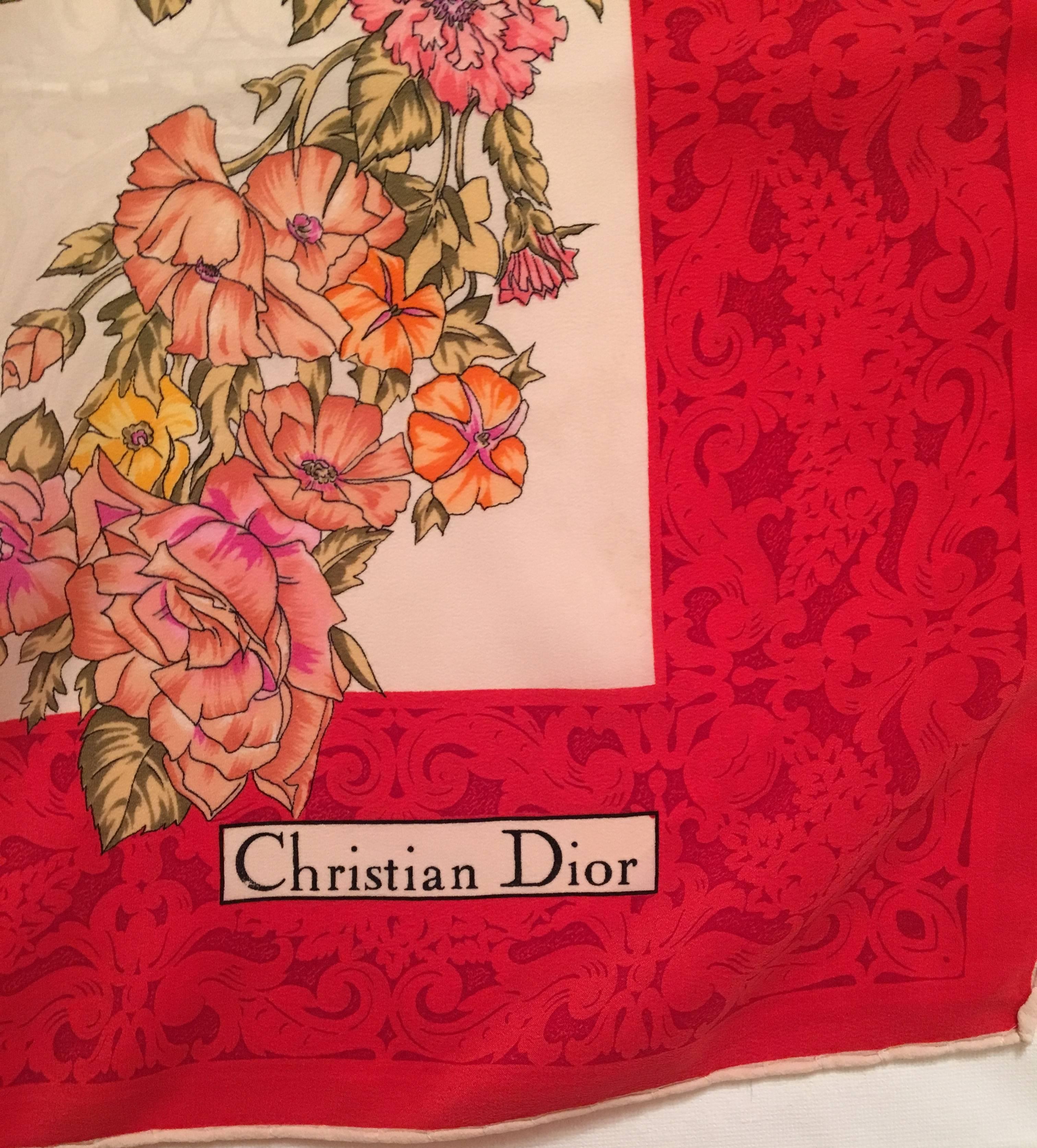 Presented here is a vintage Christian Dior scarf from the 1980's. The scarf has a rich red border with flowers of yellow, orange, peach, red and pink throughout the design of the scarf. Within the red border, there is dark red flowered print that