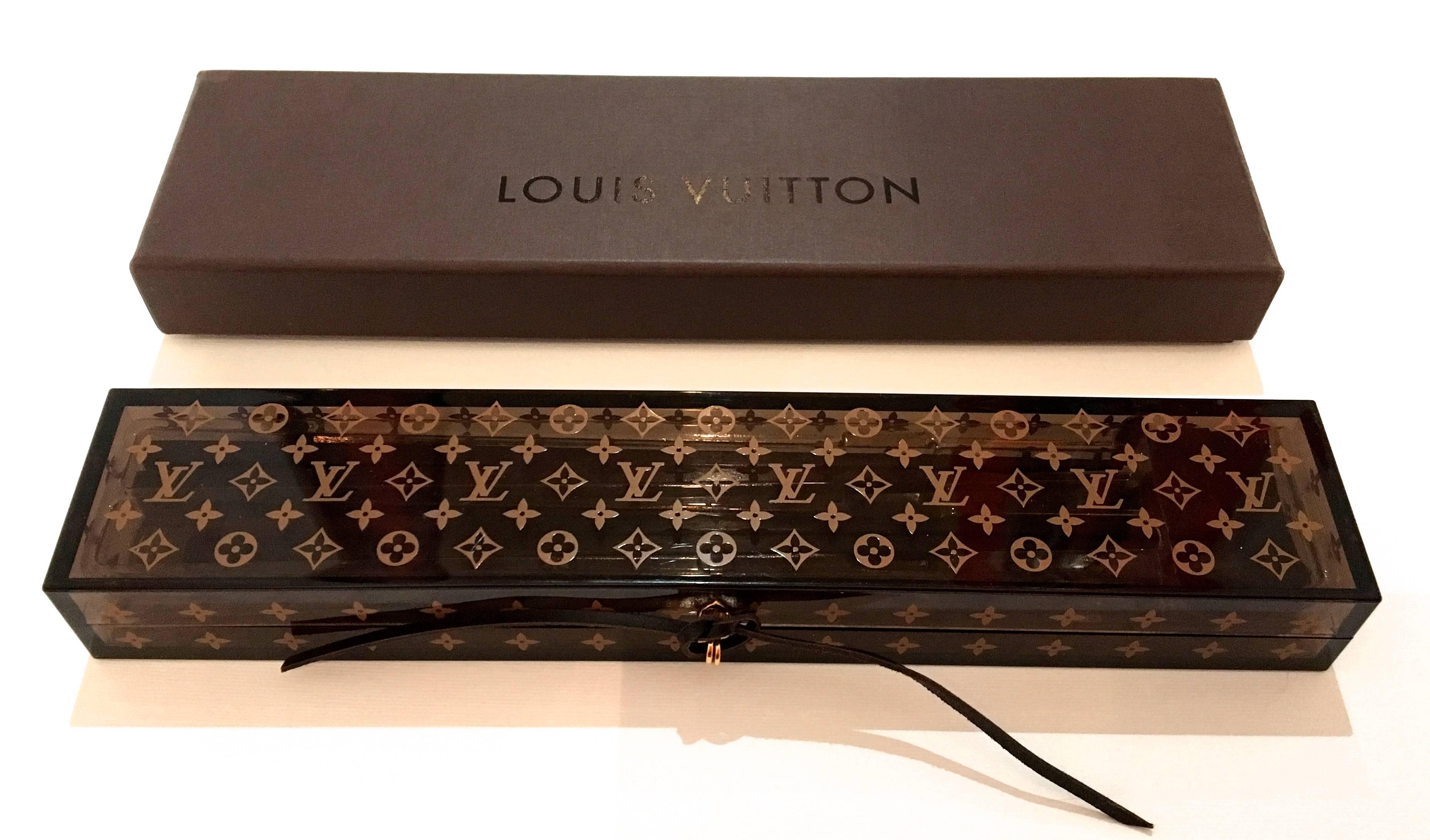 Presented here is a rare Louis Vuitton chop stick set. The set includes two pairs of chop sticks, two chop stick rests, hard lucite case for the chop sticks, and an exterior cardboard box to hold the lucite case. Each chop stick is crafted from two