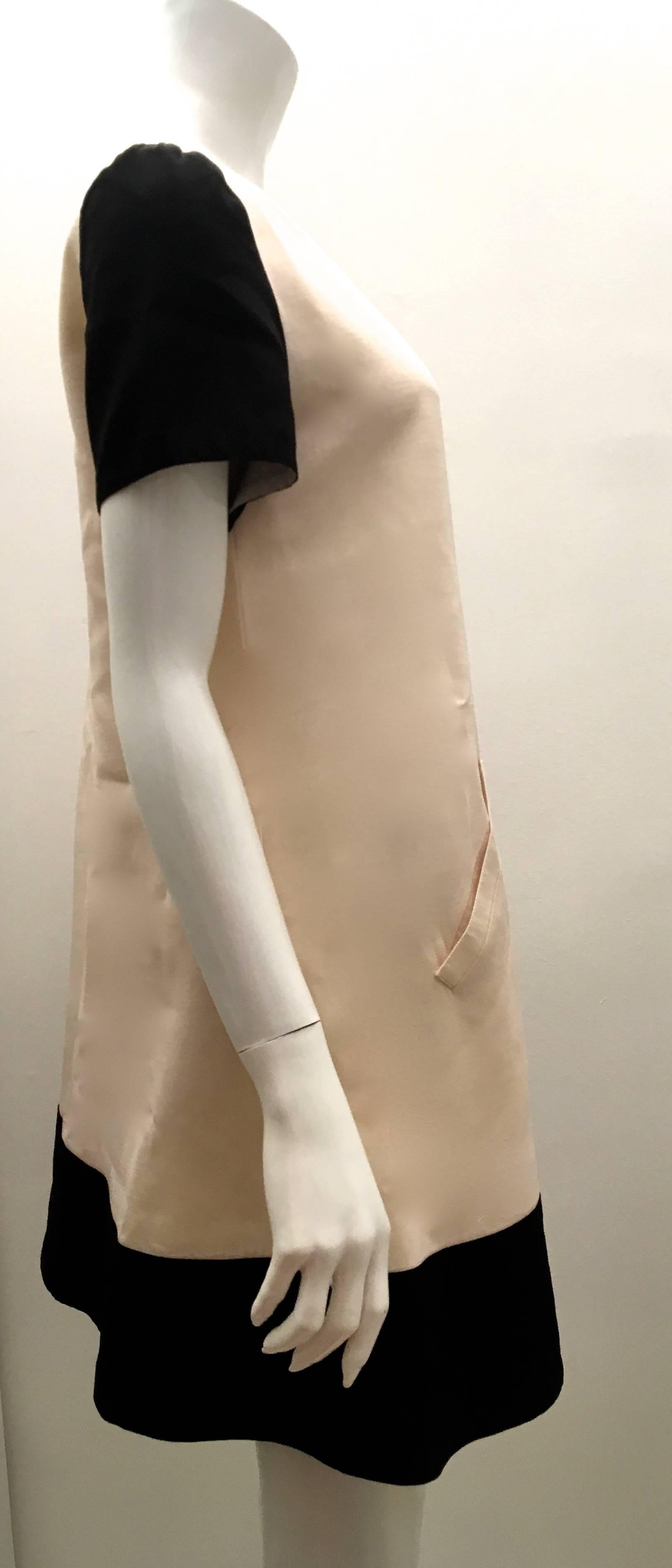 Presented here is a beautiful Courreges dress. The dress is a size 38. The dress is solid white throughout and has a thick black border trim on the sleeves and bottom hem of the dress. There are two front pockets on the dress. The dress's exterior