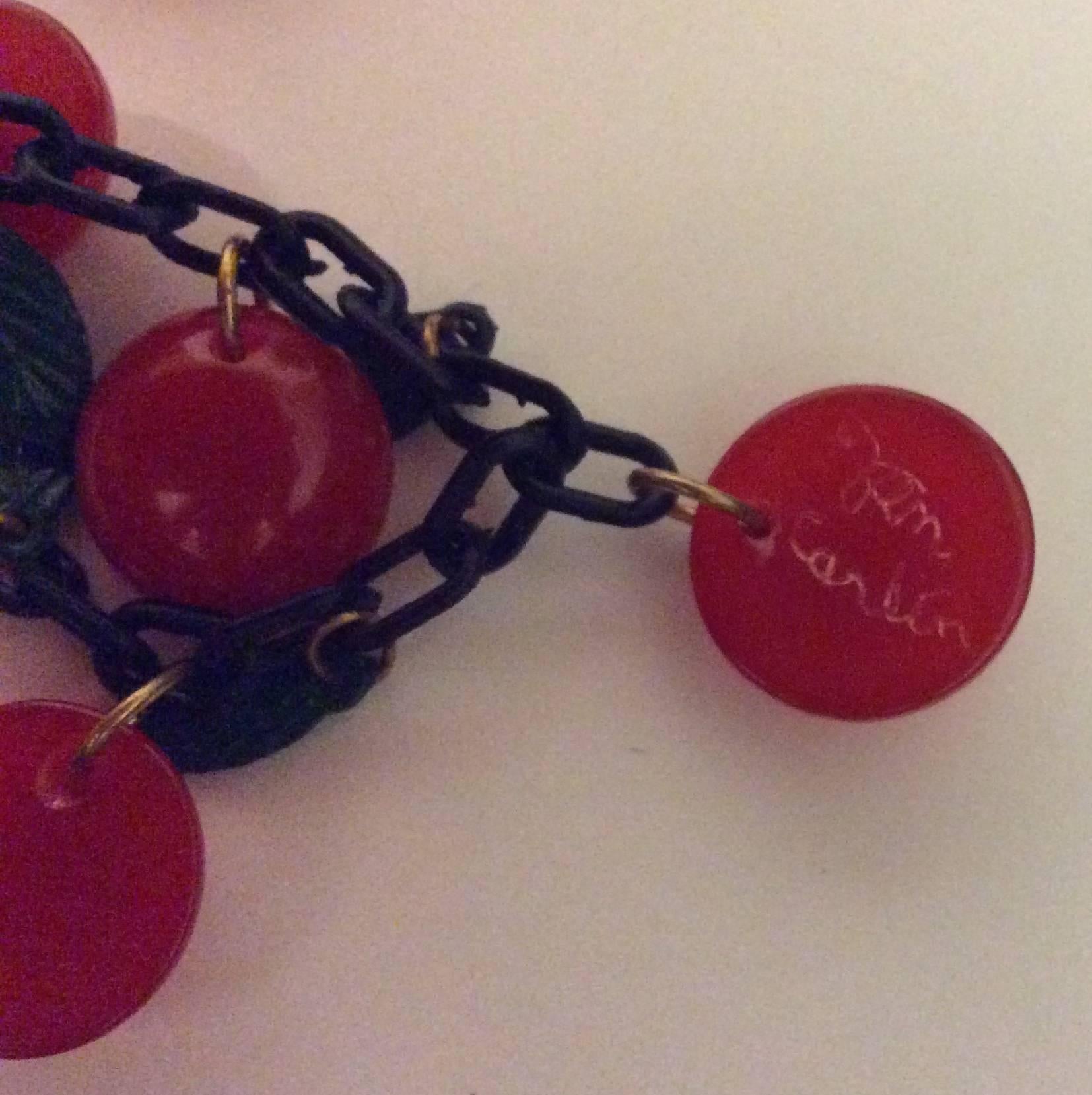 This beautiful cherry necklace with matching earrings is a gorgeous example of bakelite jewelry at its very finest. The earrings are clip-on cherries and the necklace is a series of leaf and cherry charms on a black chain. The set is signed by the