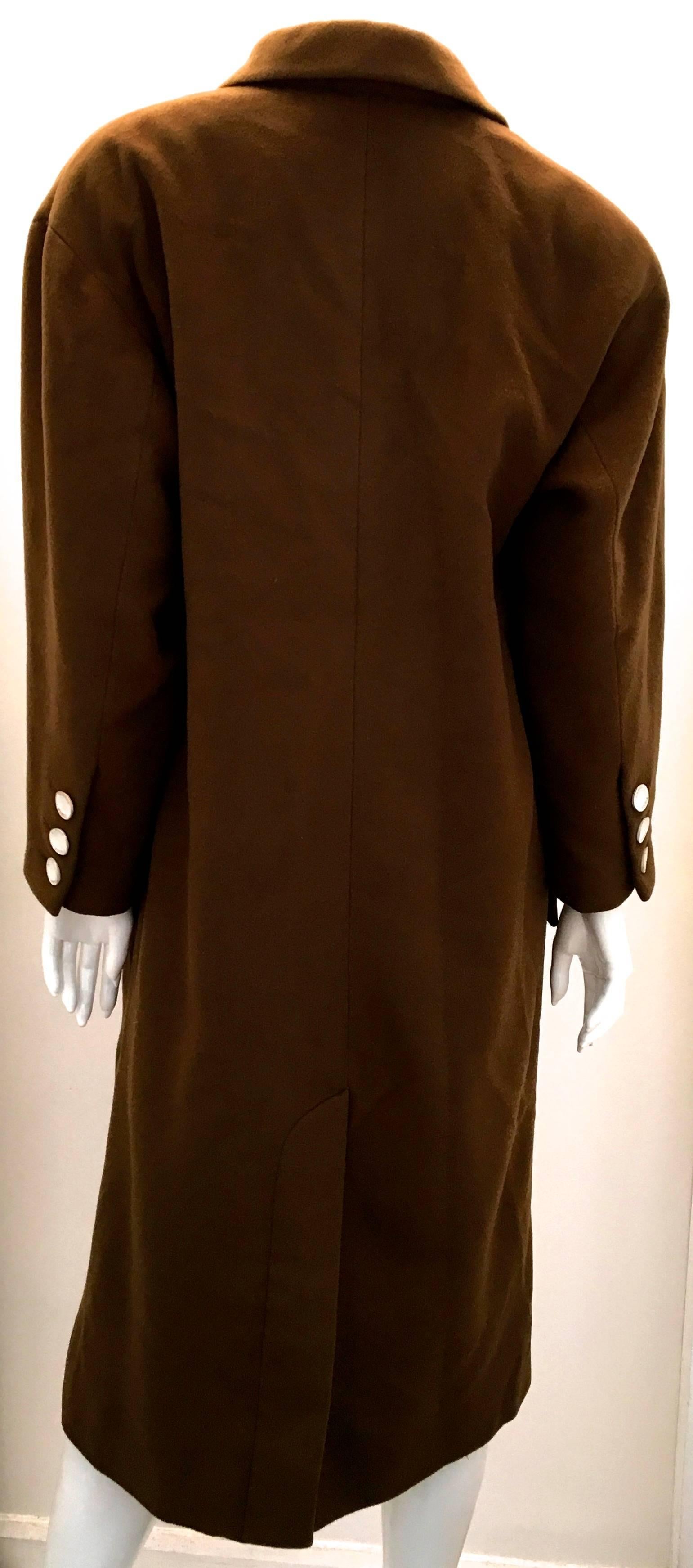 Presented here is a magnificent tobacco brown cashmere coat from Chanel. The coat is made of 100% cashmere. The coat is from the 1980’s, but has recently had the buttons replaced by Chanel. The buttons are made out of white enamel with gold toned