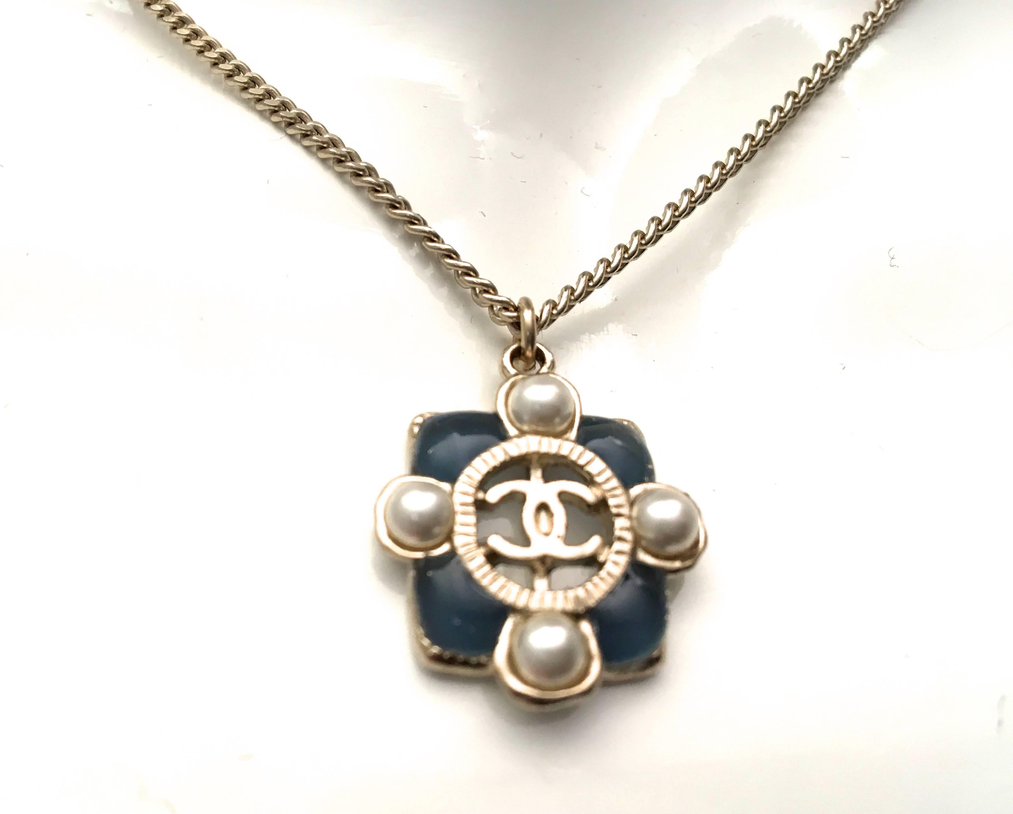 Presented here is a new Chanel medallion necklace from the 2015 collection. The medallion is comprised of a square medallion with a pearl on each side of the square. On each corner of the medallion there is a gripoix stone that is dark blue. The