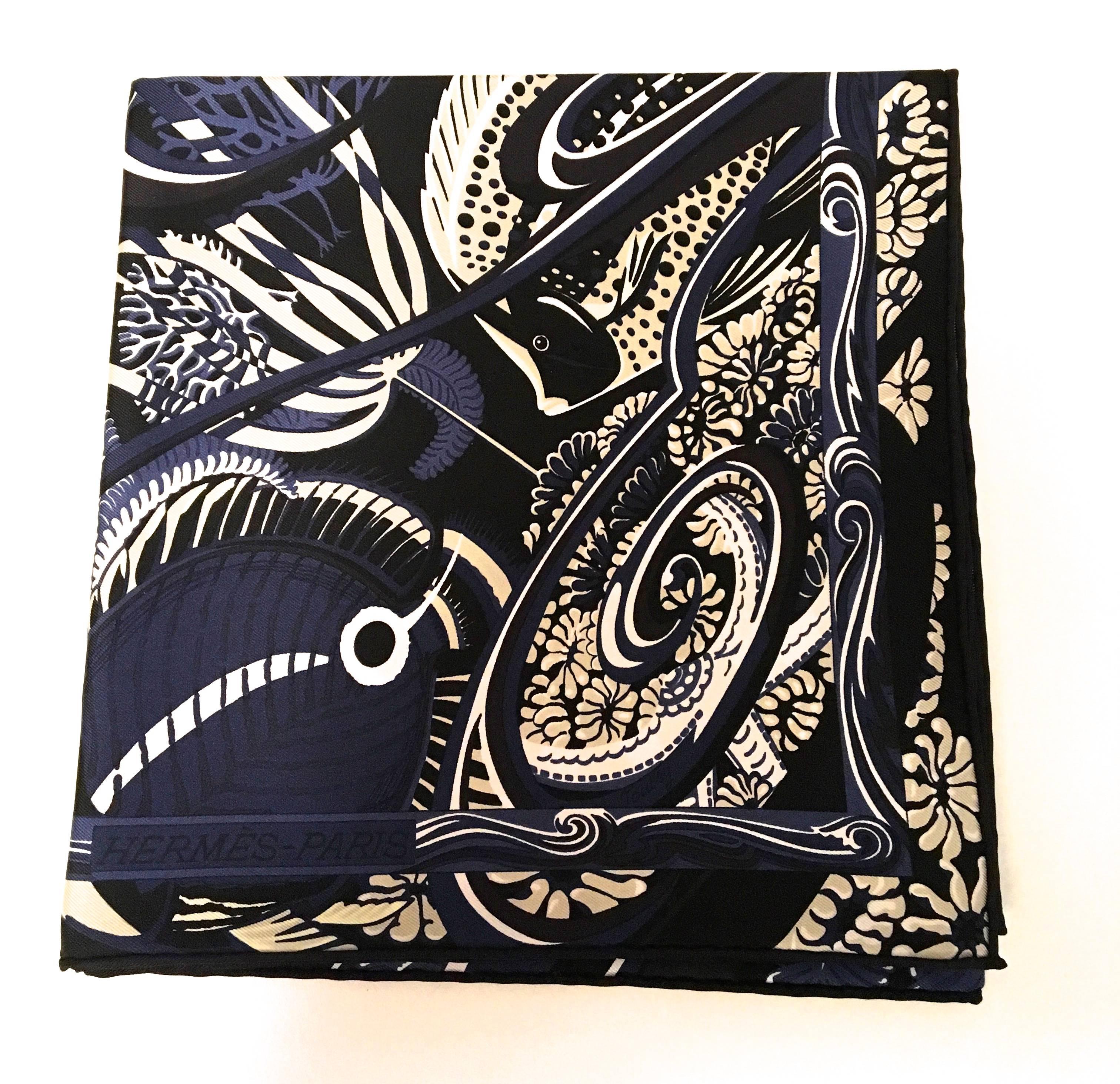 Presented here is a new Hermes blue fish silk scarf. The pattern is comprised of colors of blue, white, black, beige, and gray. The scarf is comprised of images of fish swimming down a stream of water. A gorgeous design that is a masterpiece by the
