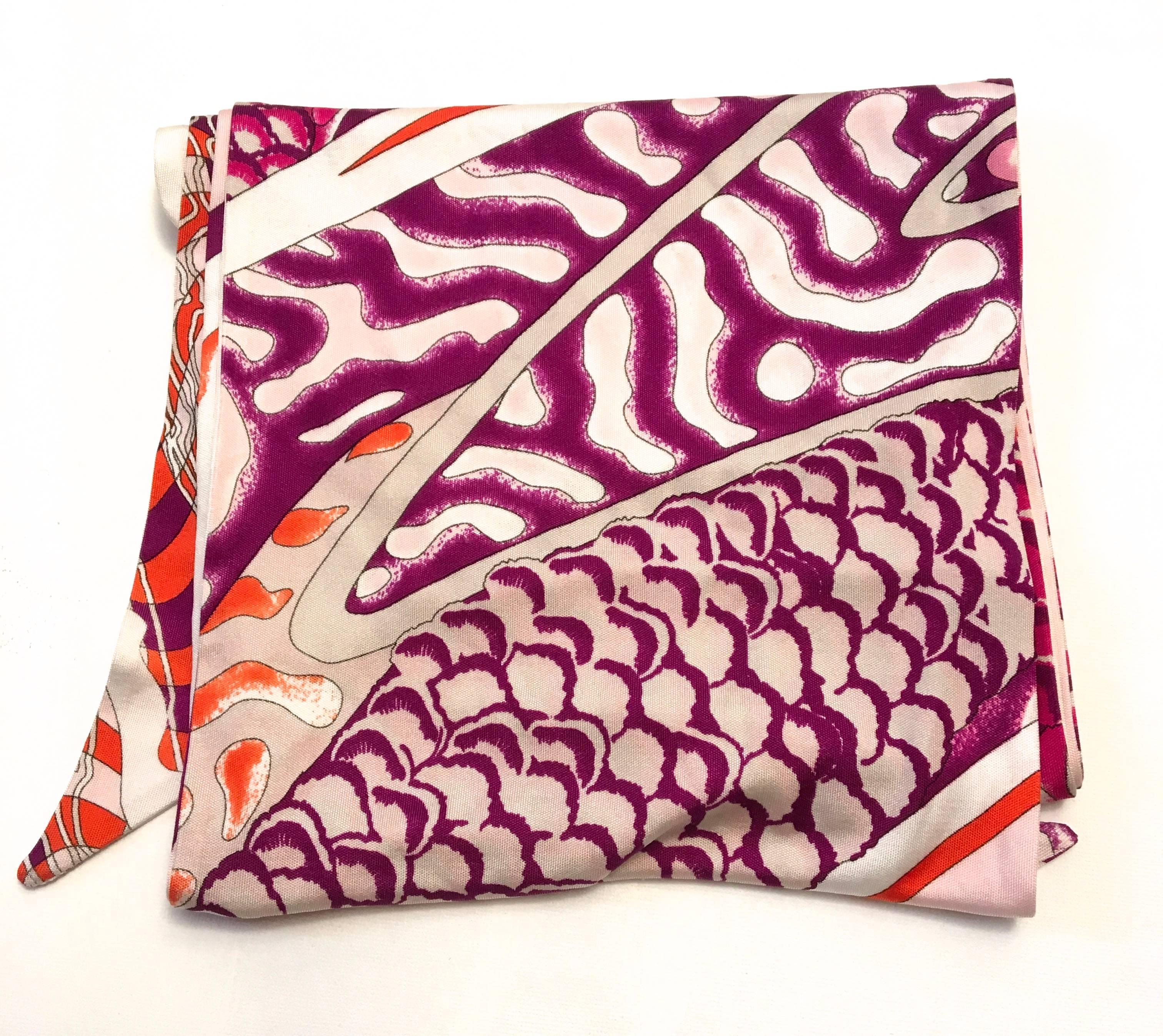Presented here is a beautiful scarf from Emilio Pucci. The scarf is made of a silk jersey material that has a bit of stretch to it. The pattern is a fish scale Koi pattern and is comprised of white, magenta, lavender, purple, and orange in the