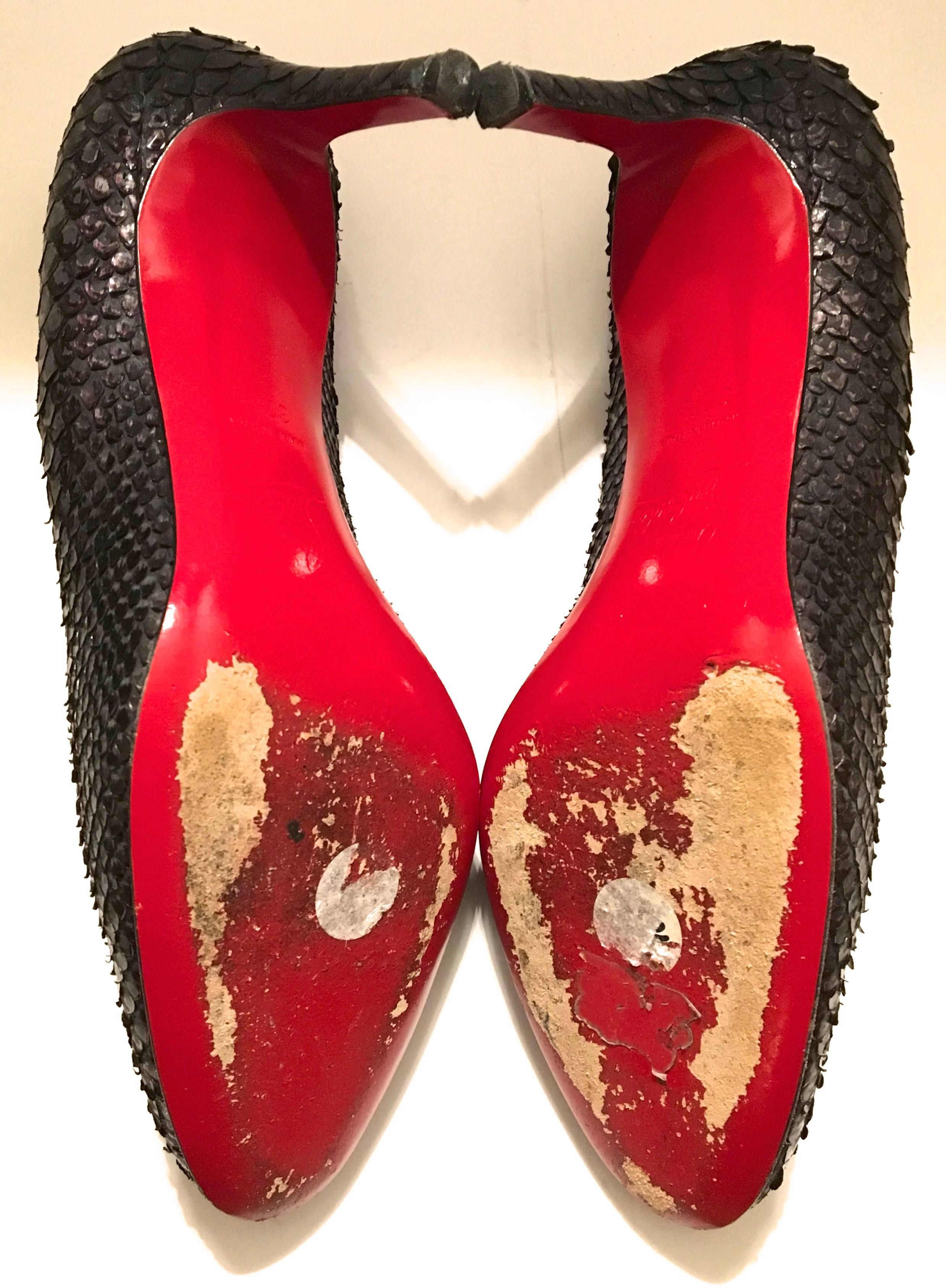 Presented here is a pair of python Christian Louboutin heels in size 37.5. The shoes have a black / charcoal gray tone to the python skin. The heels are 3 inches tall. The total length of shoe is 9.25 inches. The heels have only been worn a few