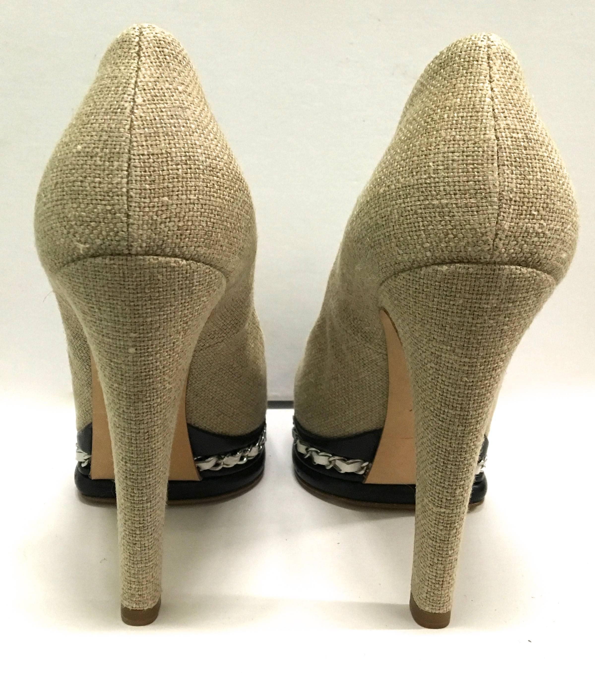 Presented here is a pair of beautiful Chanel high heels. The pair of heels is comprised of tan canvas on the exterior with black leather toes. The soles are black and also have a band of the iconic Chanel leather and metal chain wrapping around the