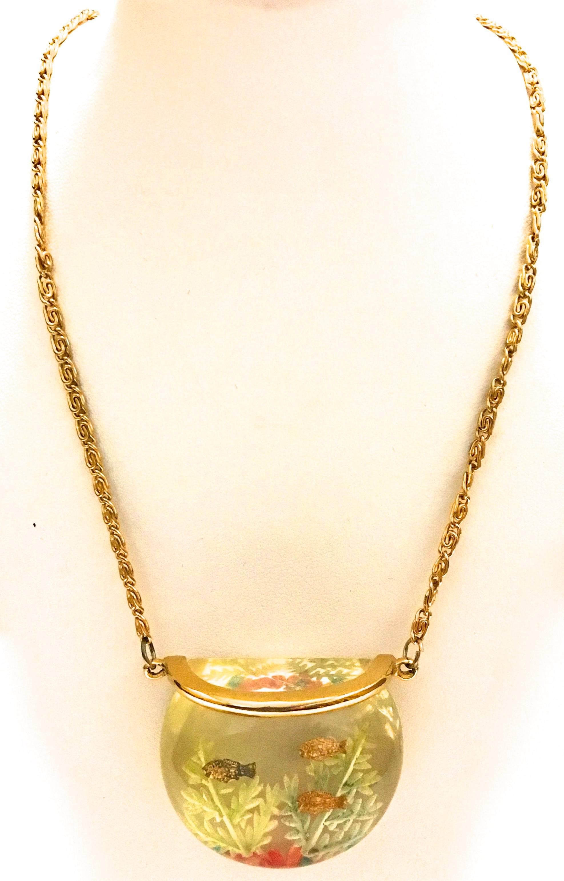 Presented here is a rare lucite fish bowl necklace. The necklace is comprised of a lucite fish bowl charm with fish and kelp charms encased inside the lucite. These necklaces have been iconic throughout fashion history and make a whimsical accent to